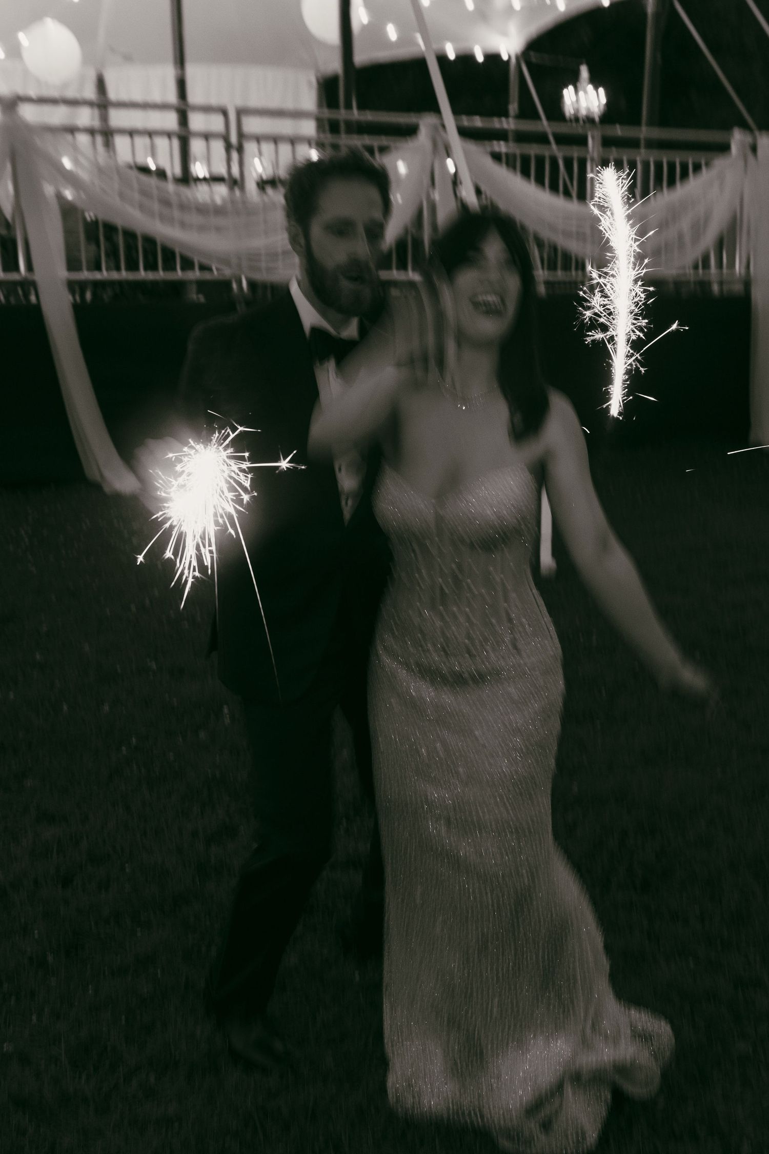 Black and white photo of wedding celebration with sparklers creating magical light trails.