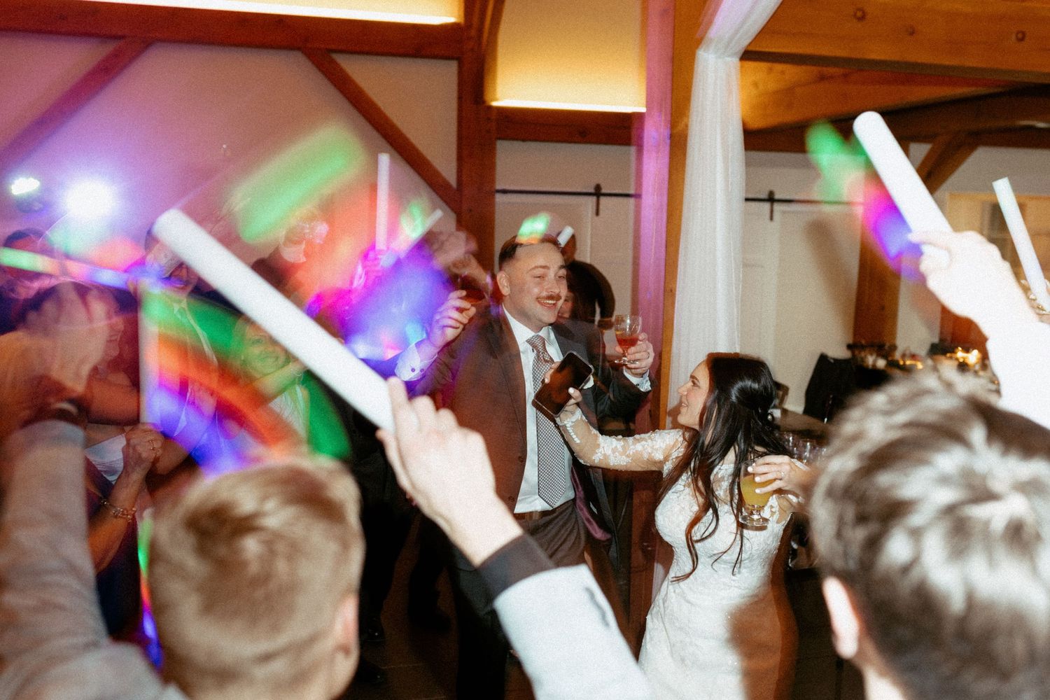 Wedding celebration with colorful LED foam sticks being waved by guests on a dance floor.