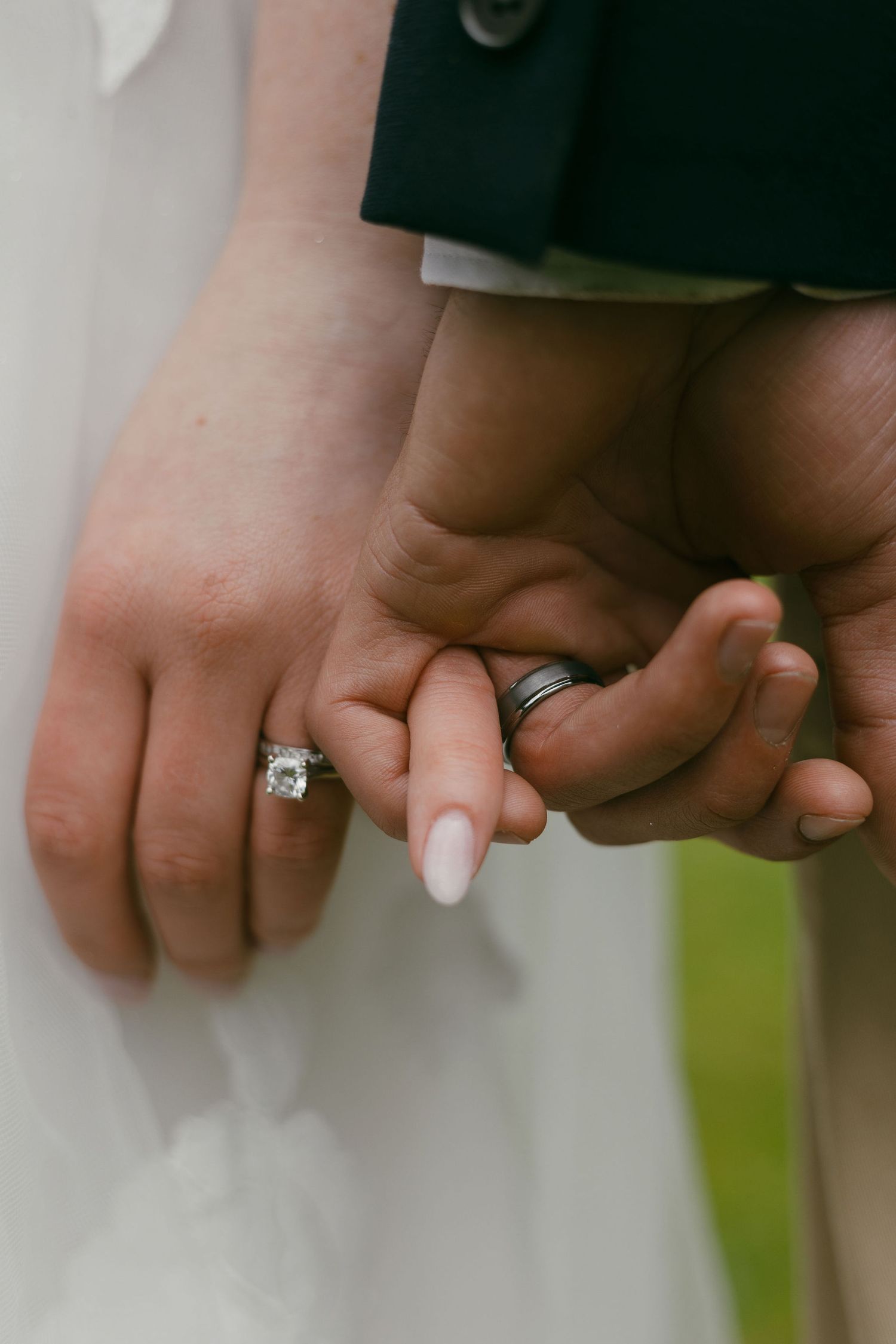 Close-up of newlyweds holding hands showing their wedding rings.
