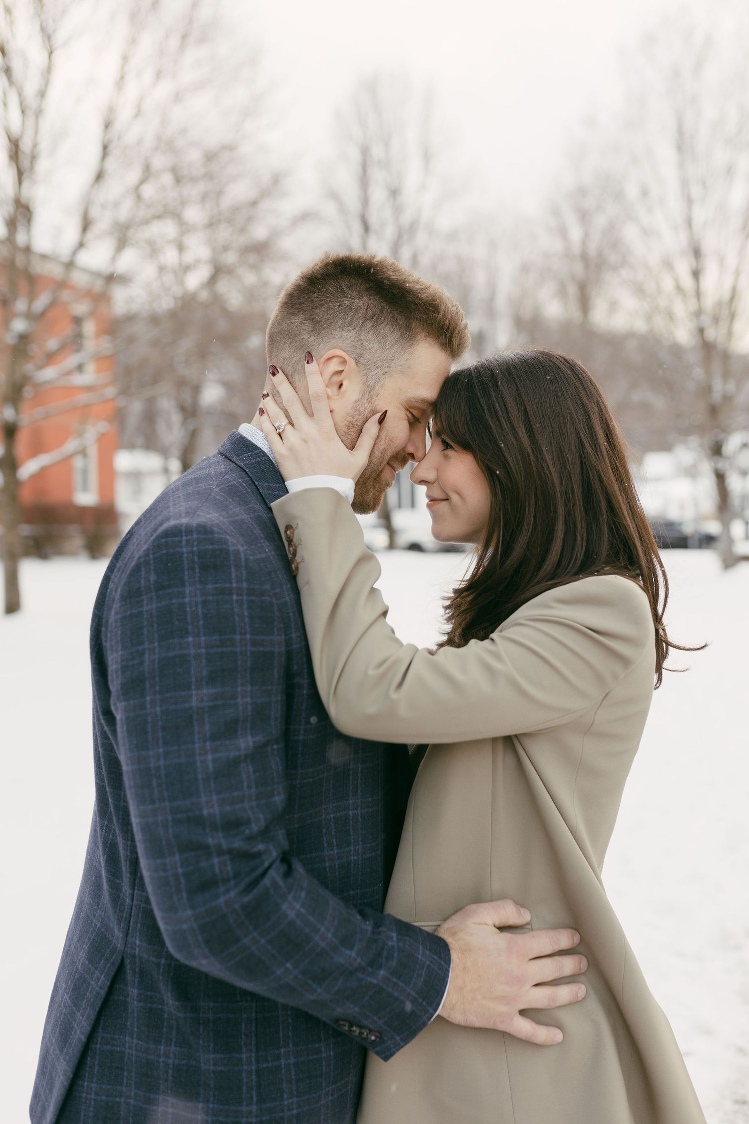 Tender embrace captured in a series of winter engagement photos with snowy backdrop.