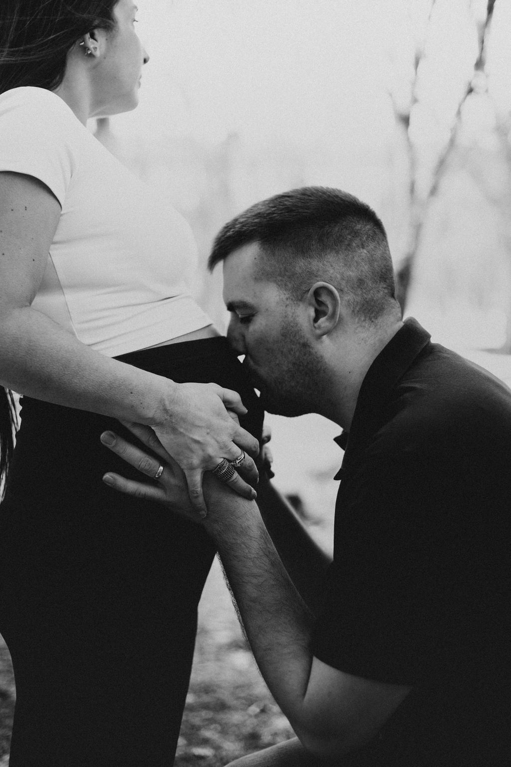 Black and white intimate maternity photos showing tender moments in an outdoor setting.