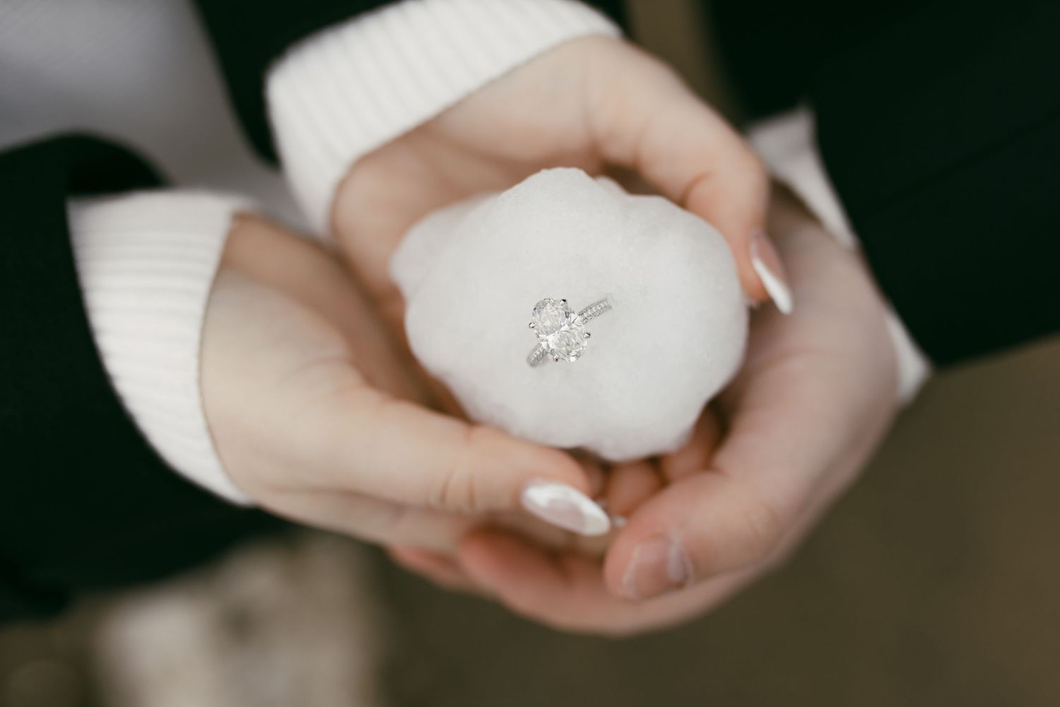 Hands gently holding a white decorative egg with cross design.