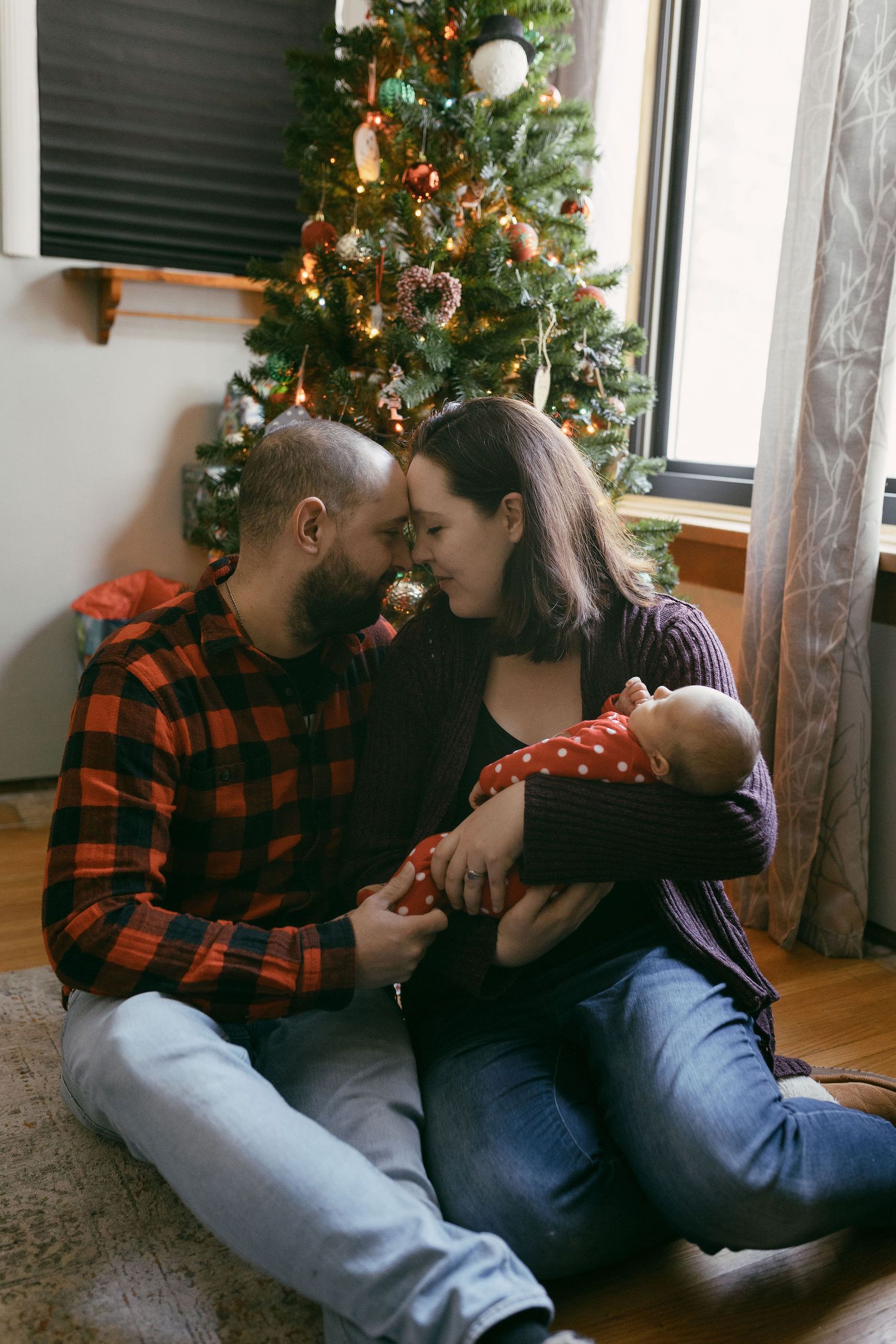 Family relaxing together by decorated Christmas tree in living room.