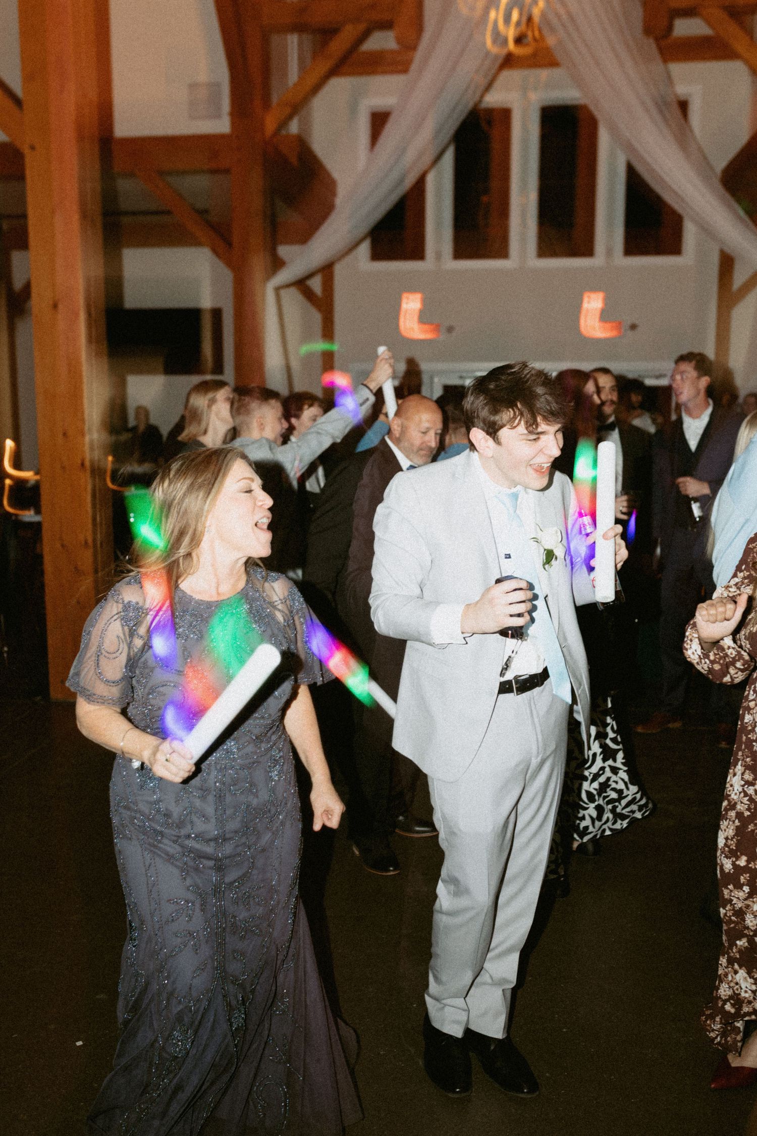 Couples dancing at a wedding reception with colorful LED lights creating a festive atmosphere.
