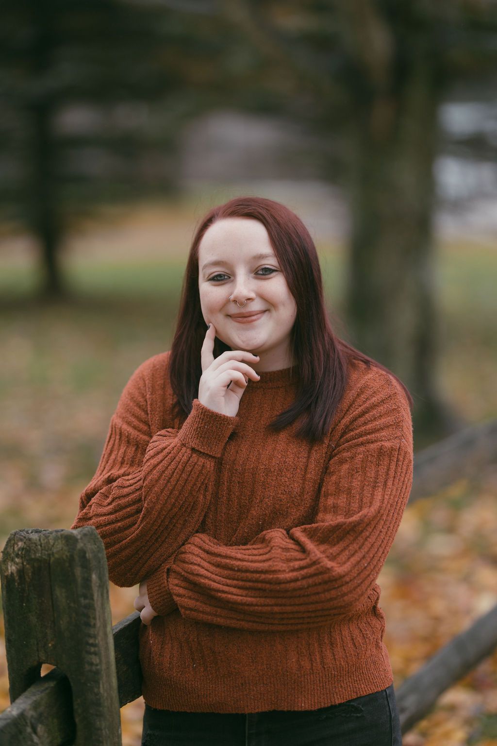 Autumn portrait series featuring cozy rust-colored sweater against fall foliage background.
