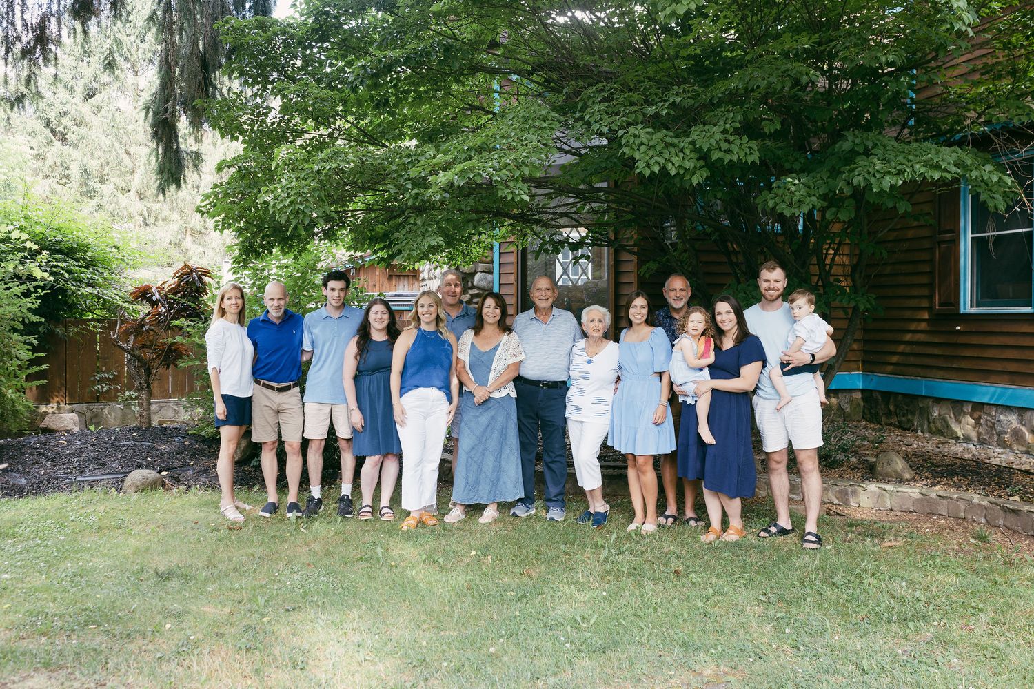 Large family group gathered outdoors for a casual photo session in a natural setting.