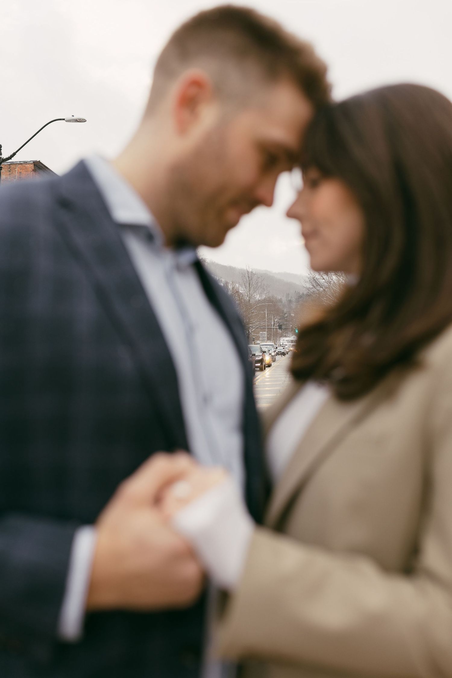 A romantic couple shares an intimate moment in soft focus against a blurred background.