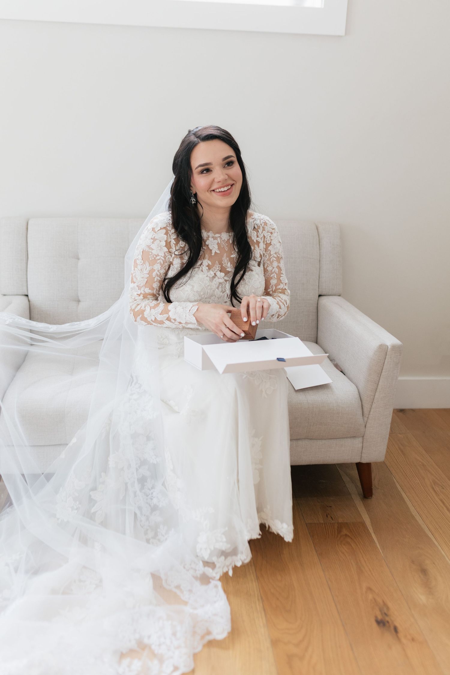 Person in white lace dress sitting elegantly in light-colored armchair.