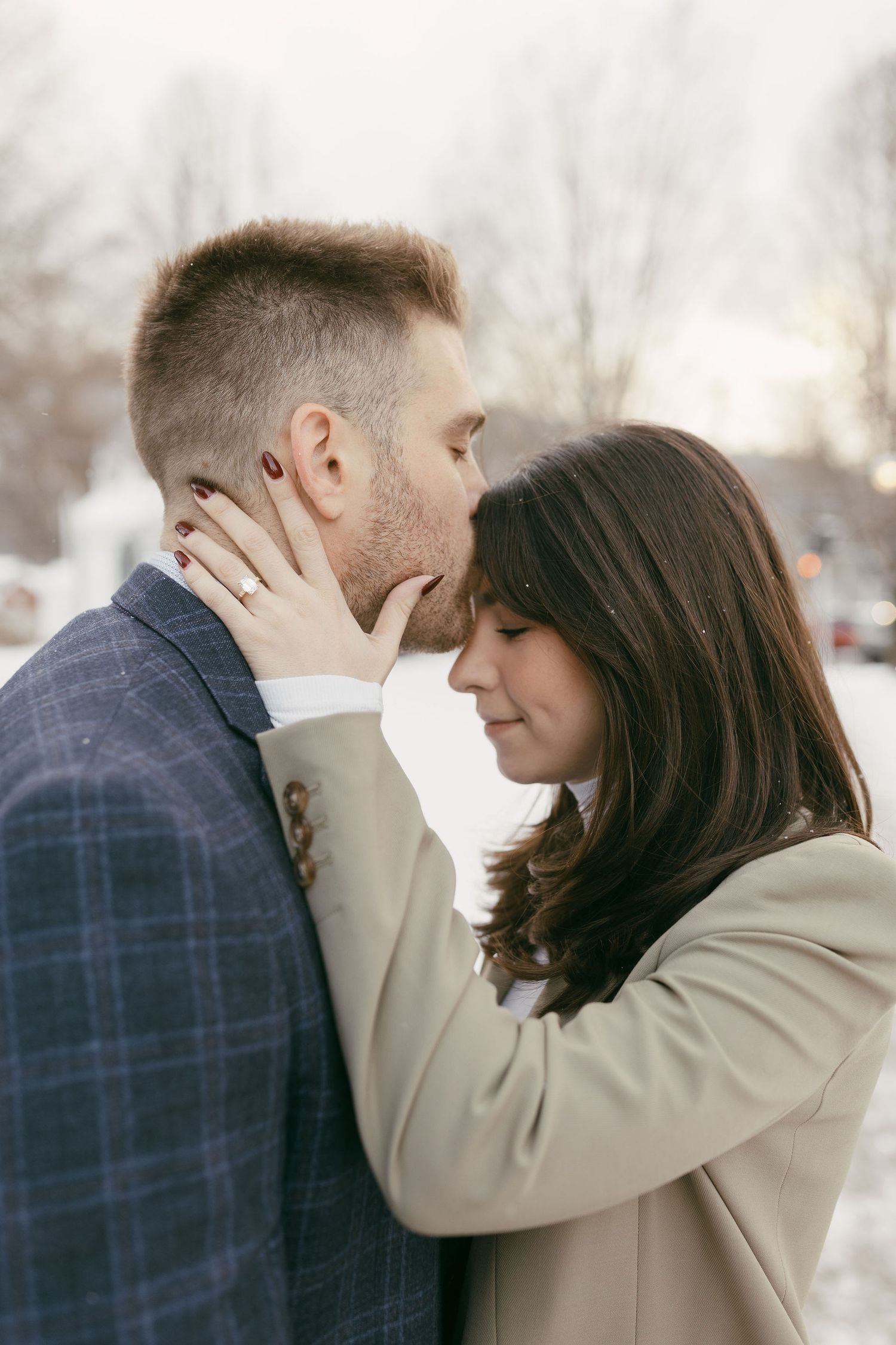 Romantic couple sharing an intimate moment outdoors in winter, woman with red nails gently holding mans face.