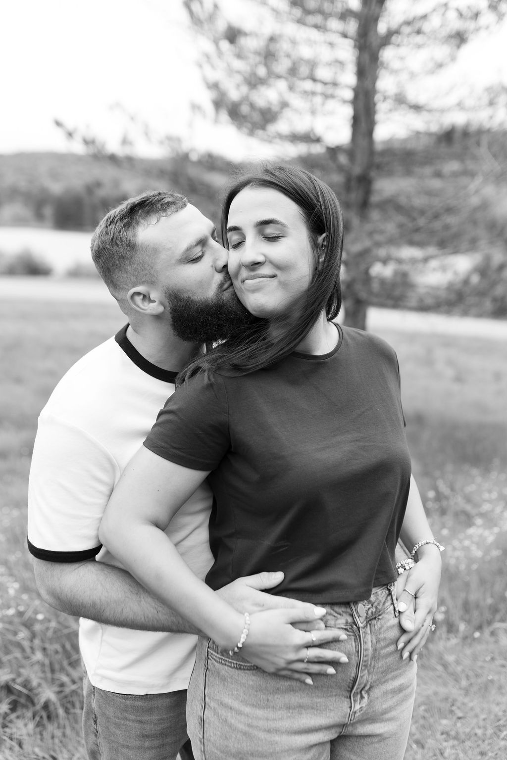 Couple in casual attire sharing affectionate moments in a field.