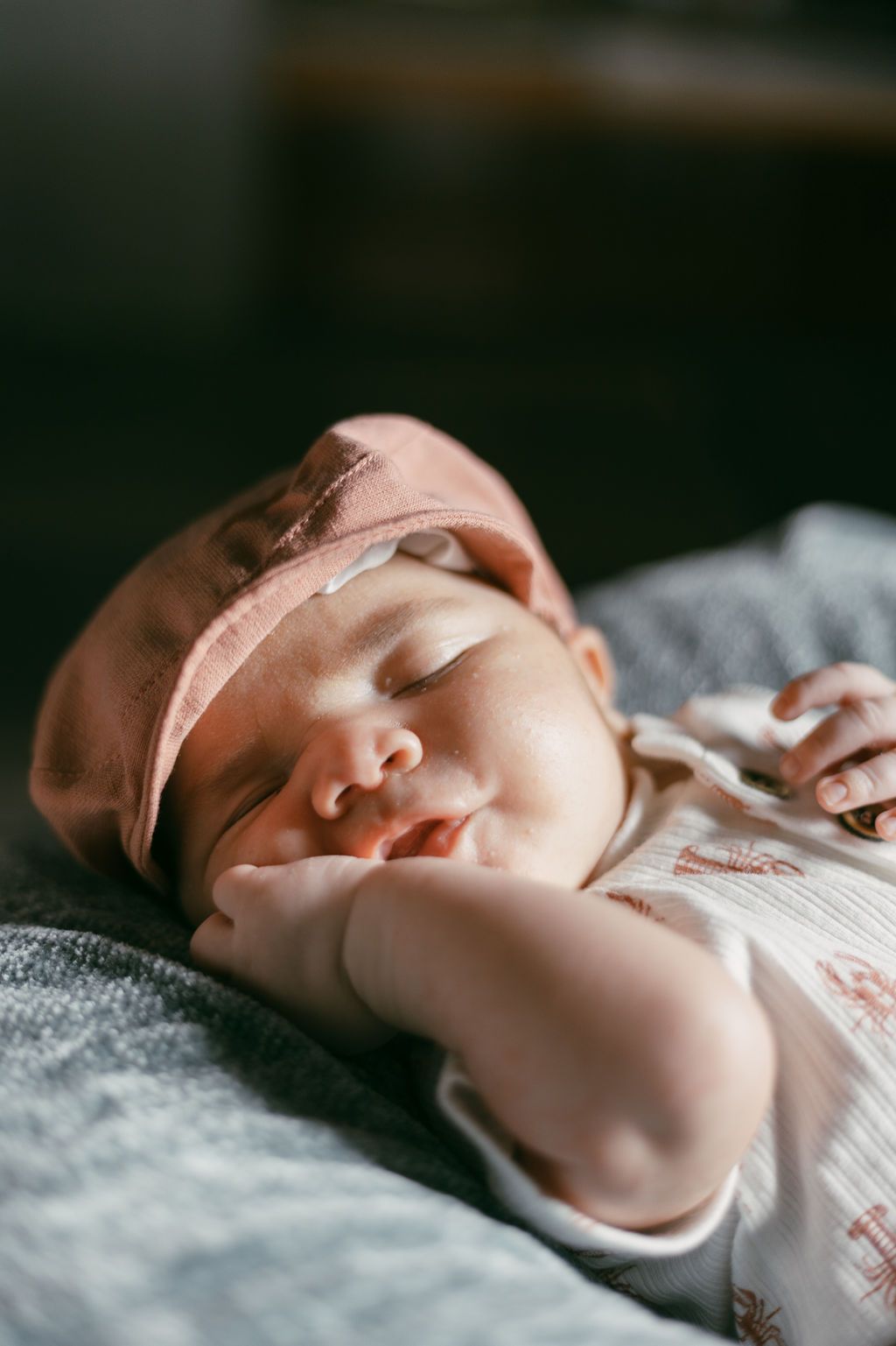 Close-up shots of sleeping newborn in natural light against gray textile.