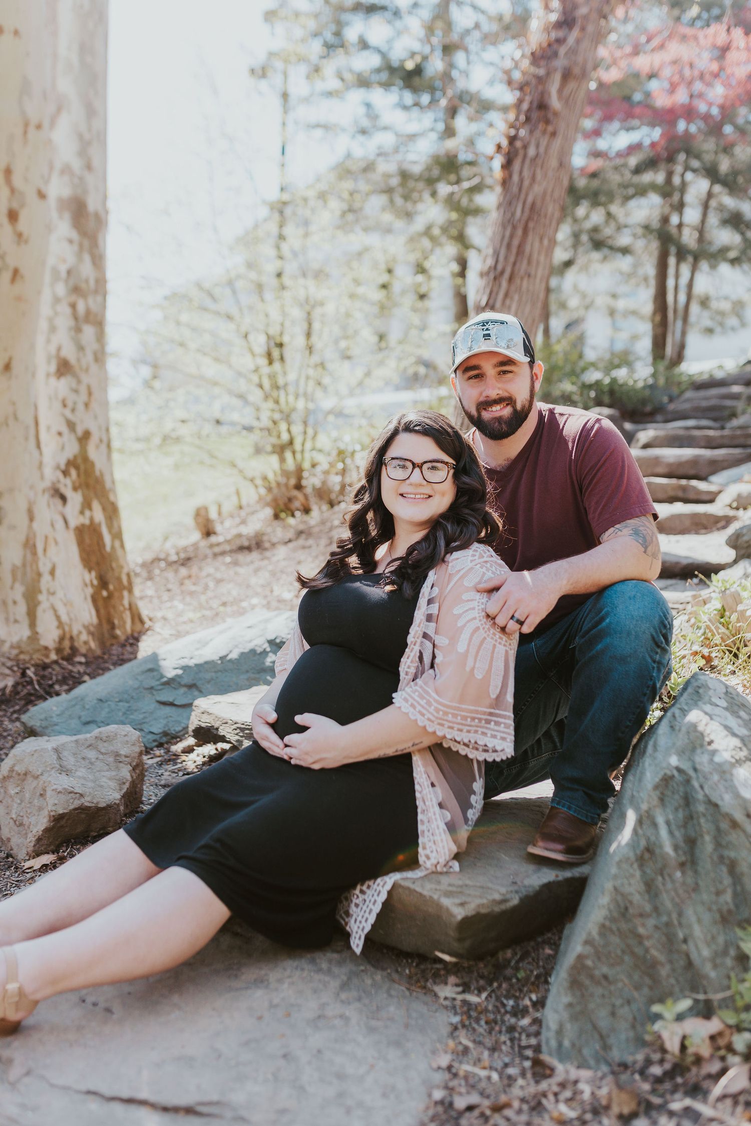 Couple relaxing together on large rocks in a wooded outdoor setting.