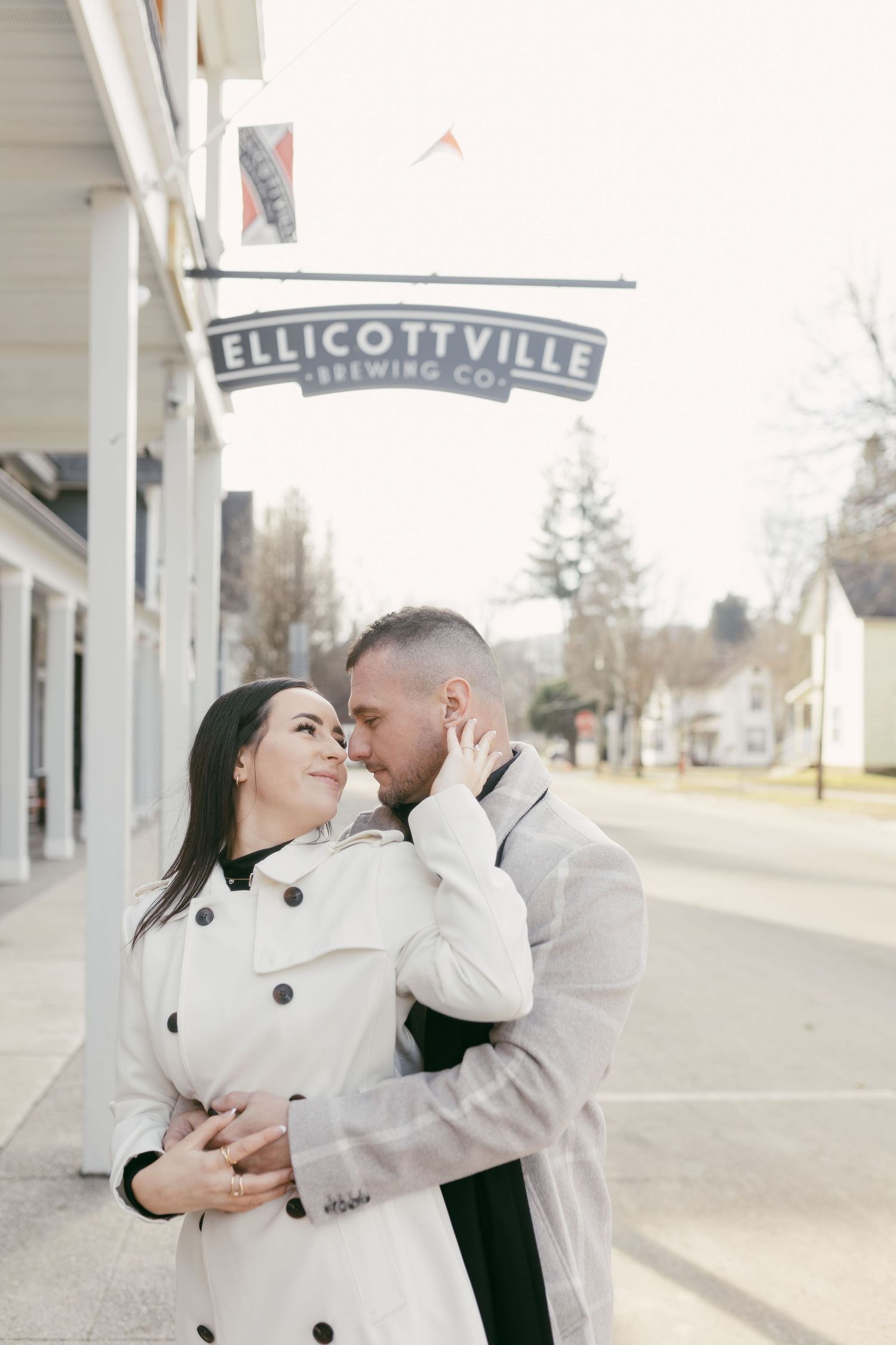 Couple embracing romantically outside Ellicottville Brewing Co. on a charming small-town street.