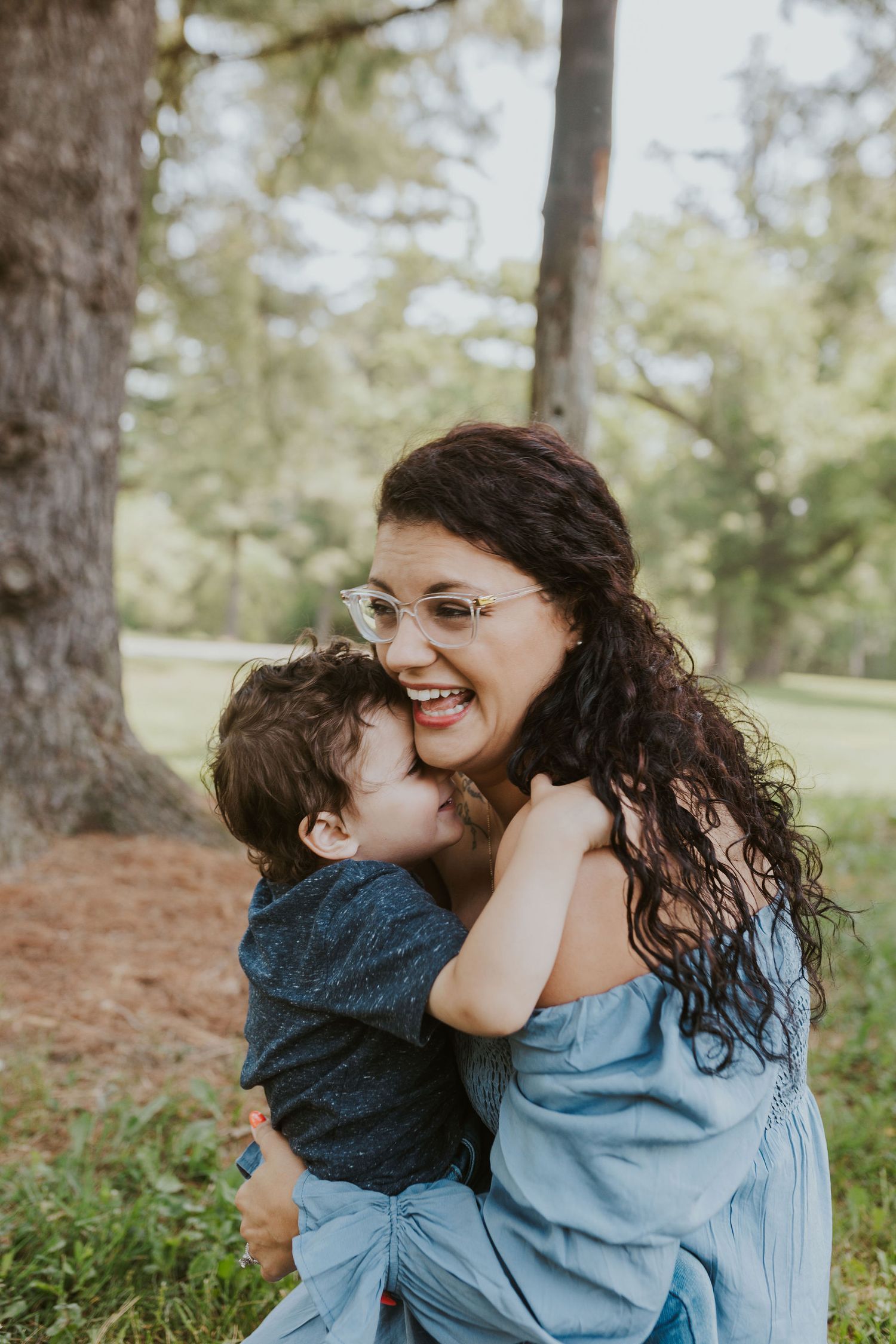 A joyful moment shared between parent and child hugging outdoors in a park setting.