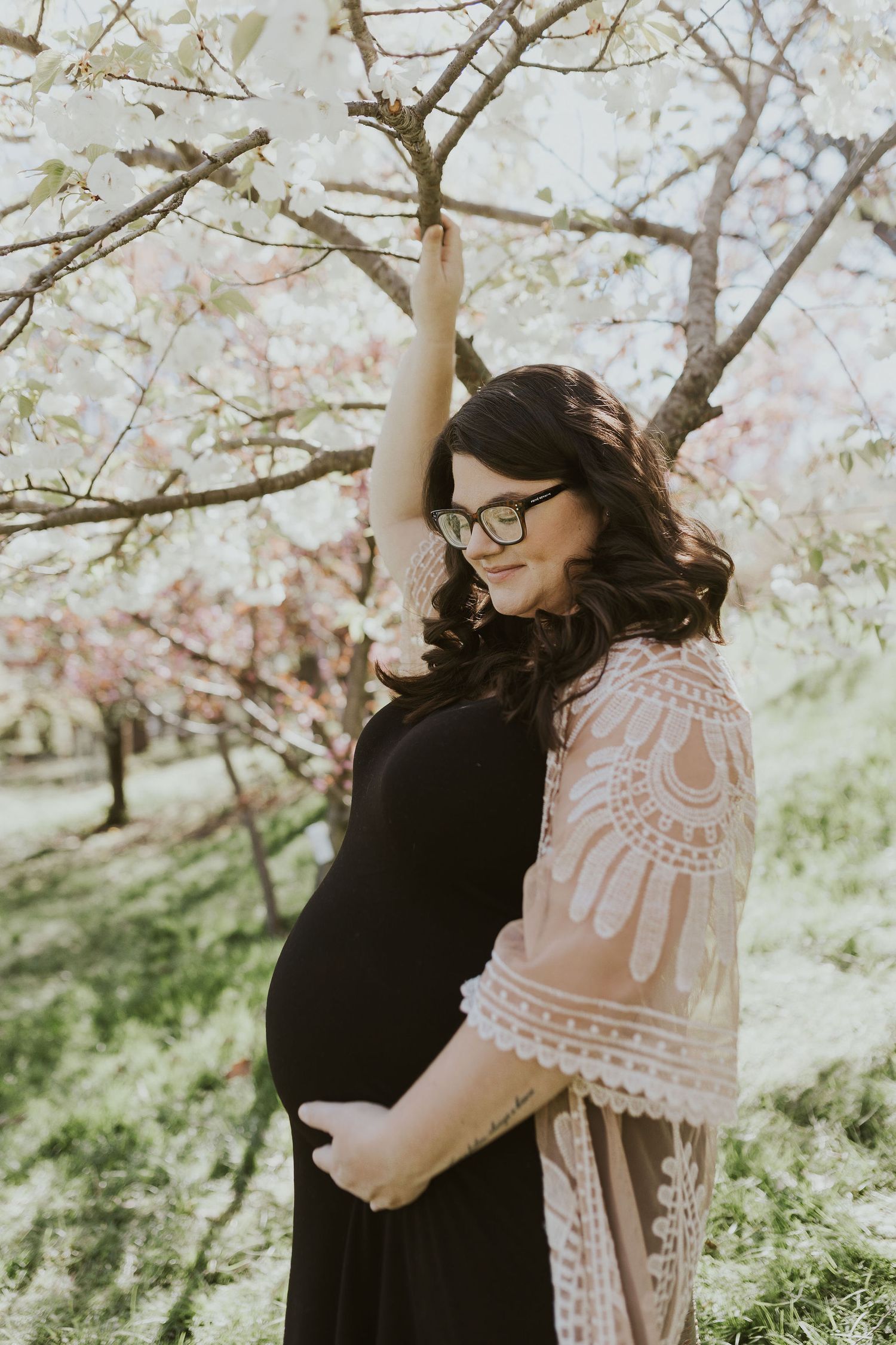 Spring photoshoot under blooming cherry blossom trees with delicate pink flowers.