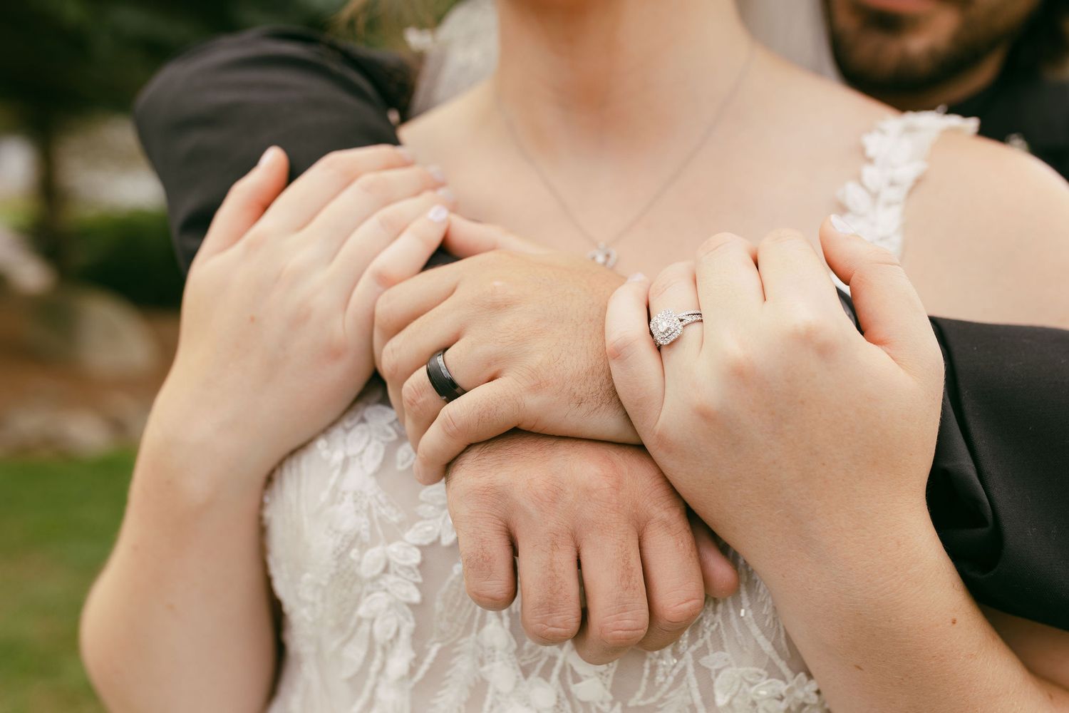 Close-up of hands showing wedding rings against lace dress details.