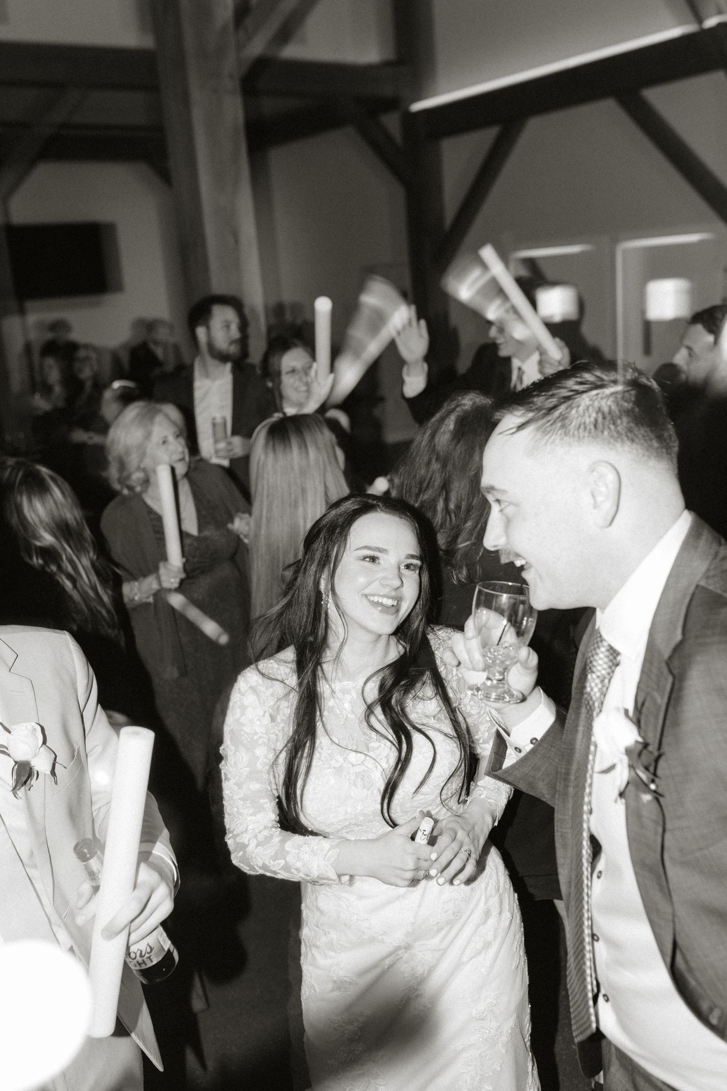 Black and white candid shots of wedding guests dancing and celebrating in a rustic venue.