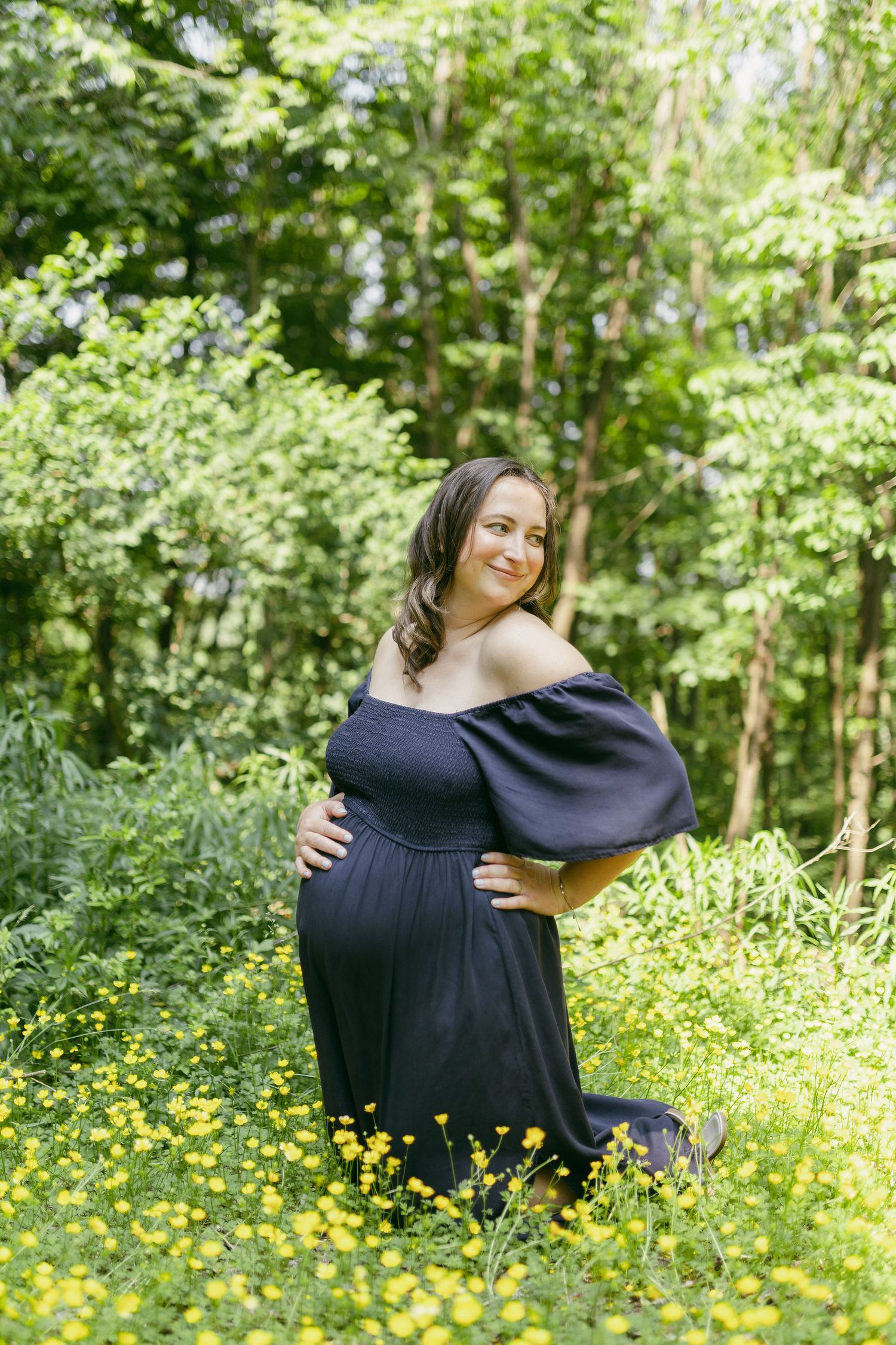 A couple embraces in a sunlit meadow with yellow wildflowers and lush green foliage.