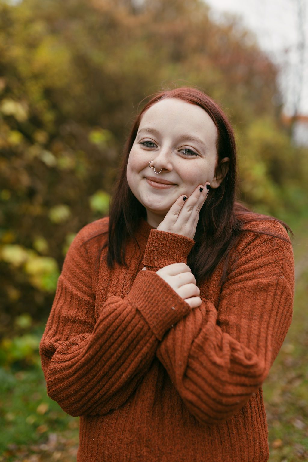 Expressive portrait series in a rust-colored sweater against autumn foliage.