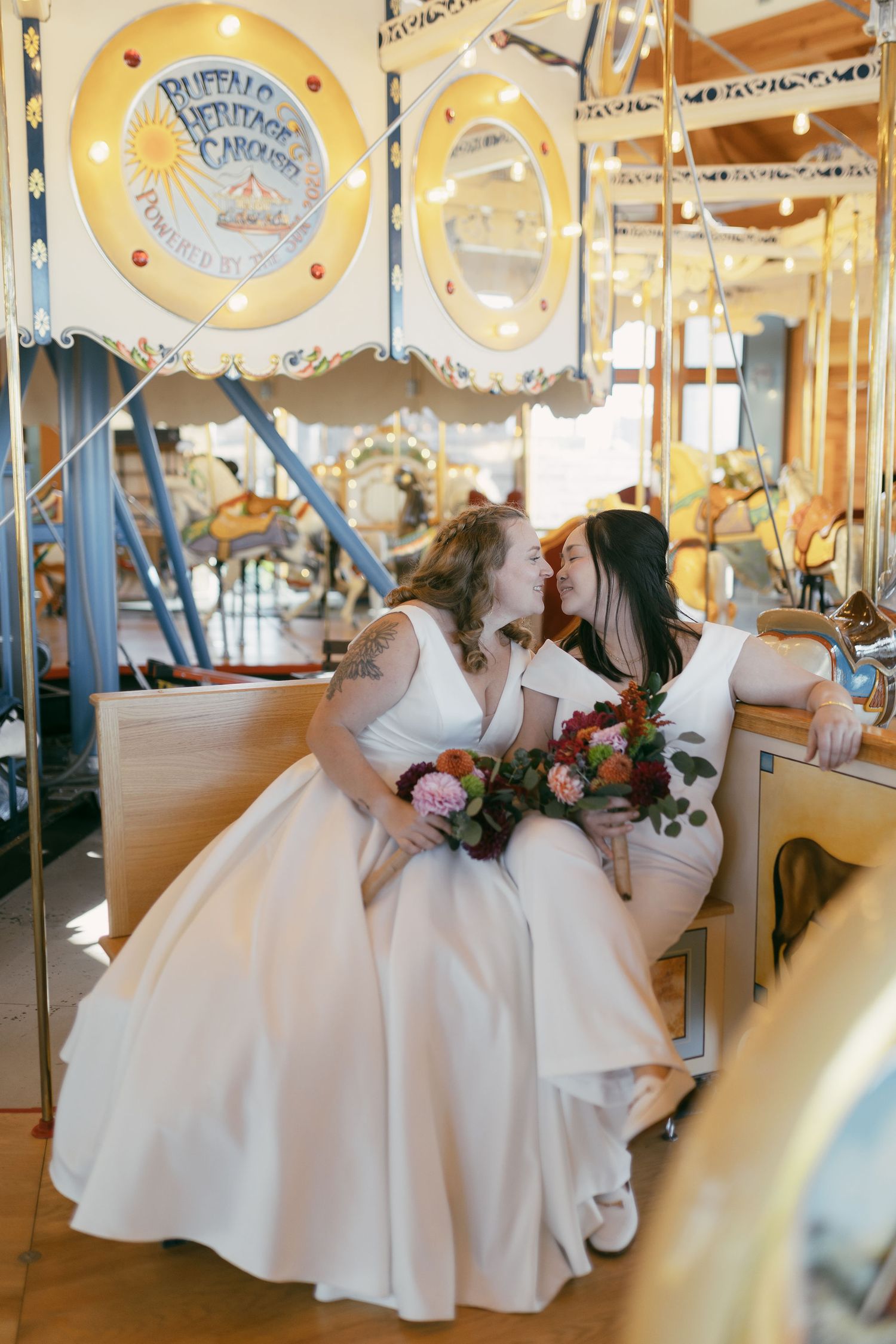 Wedding couple poses romantically on vintage carousel with decorative plates in background.