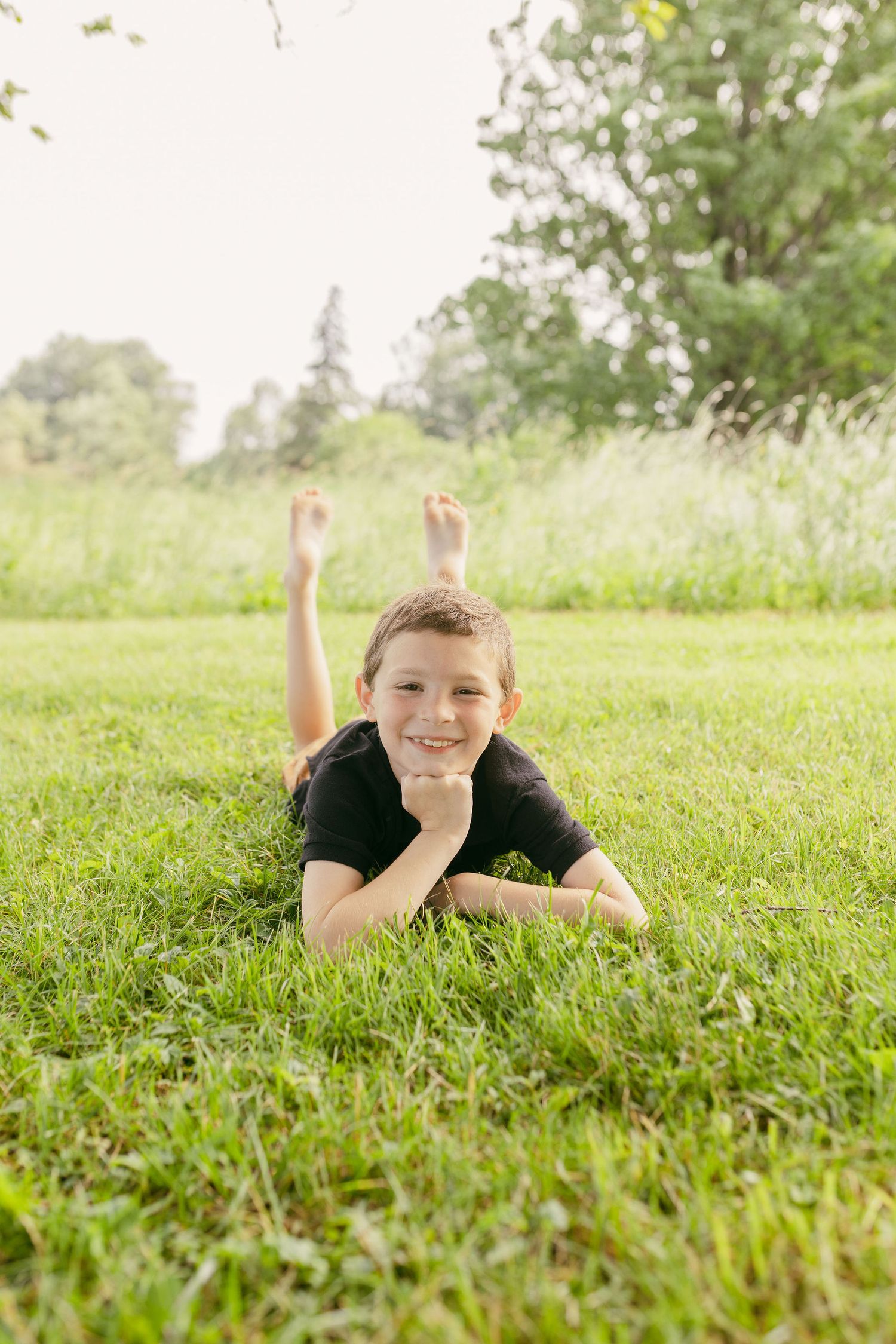 Child lying in green grass on a sunny summer day.