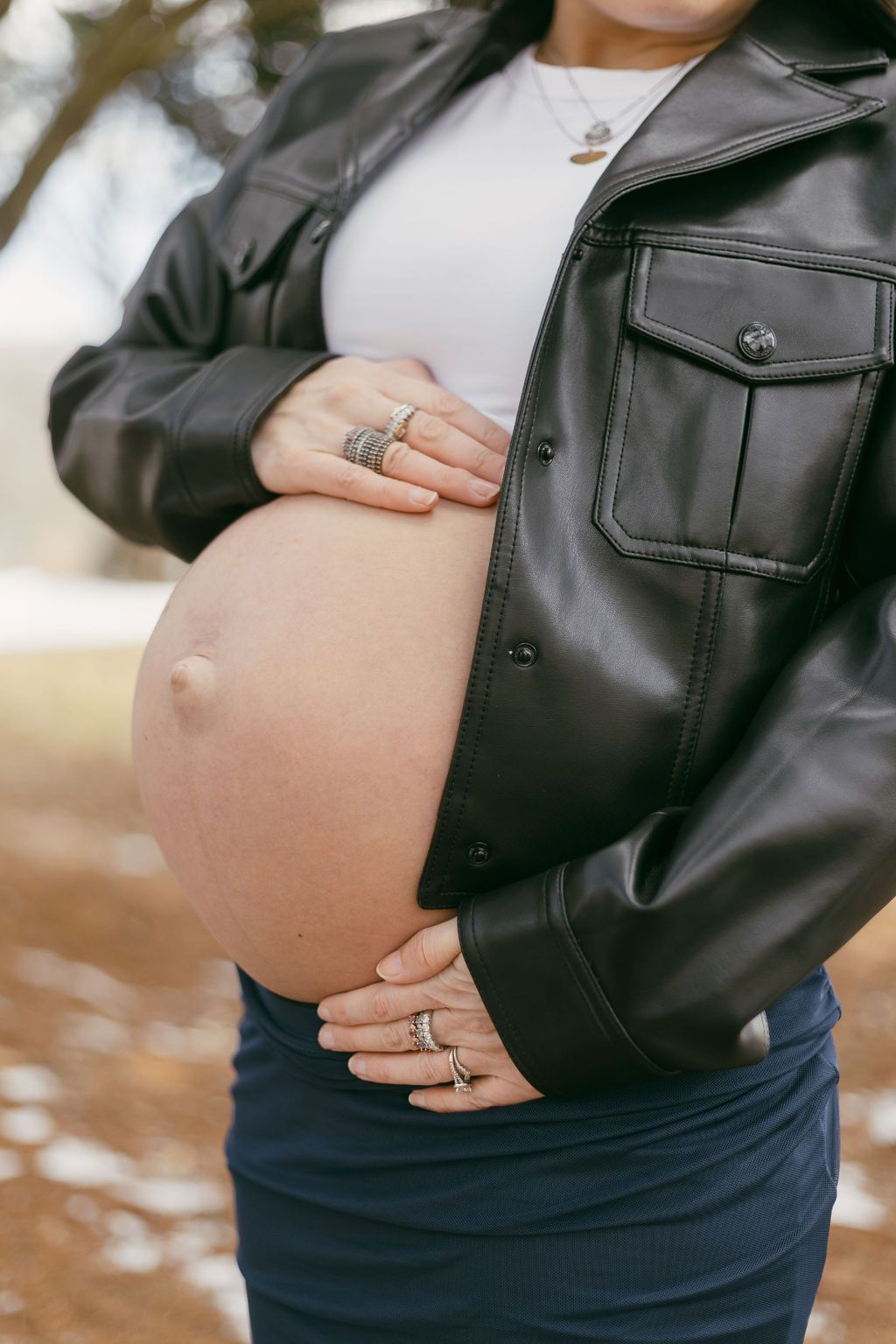 Close-up shots of a pregnant belly with hands wearing rings against dark clothing.