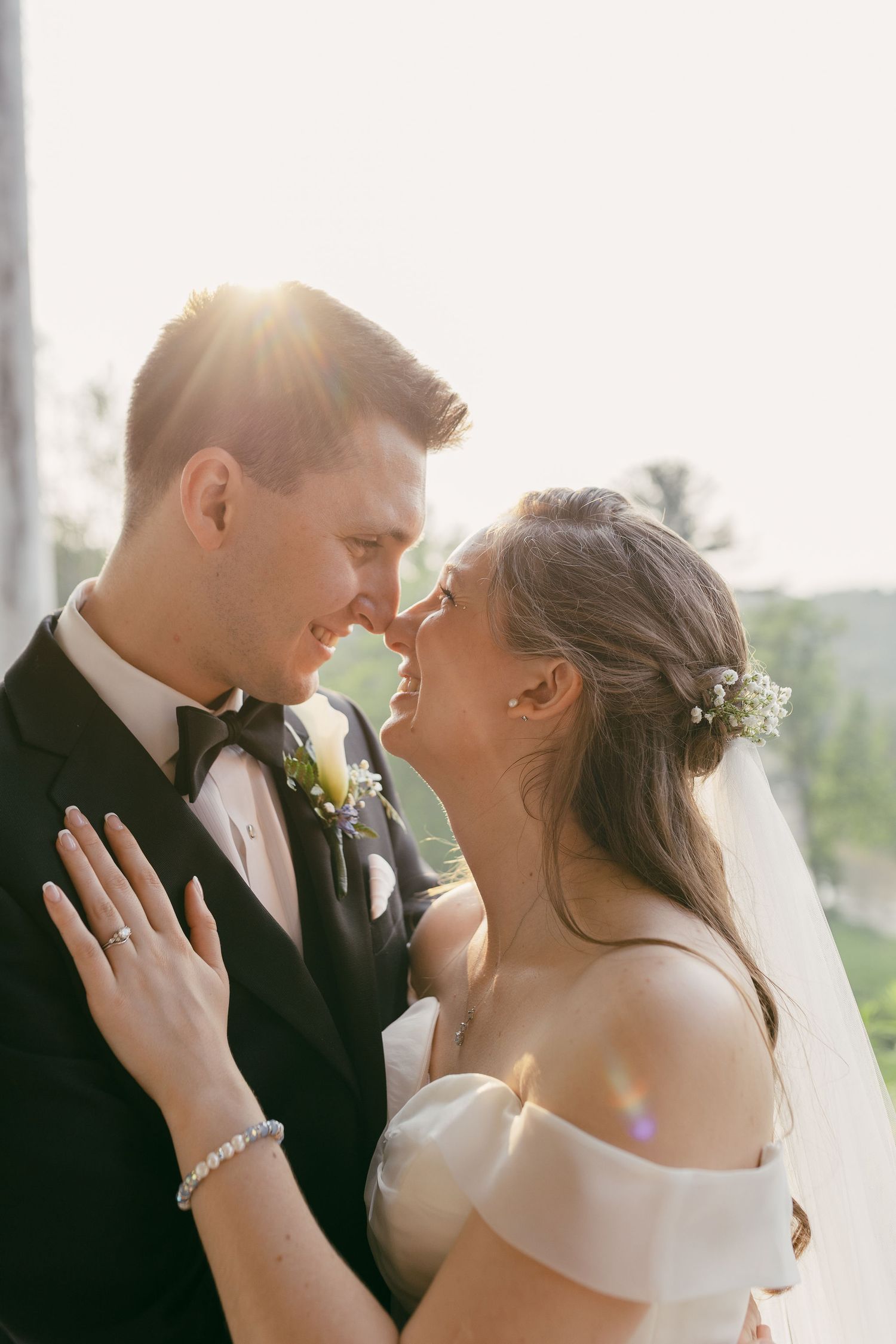 A romantic wedding portrait of newlyweds sharing an intimate moment in golden sunlight.