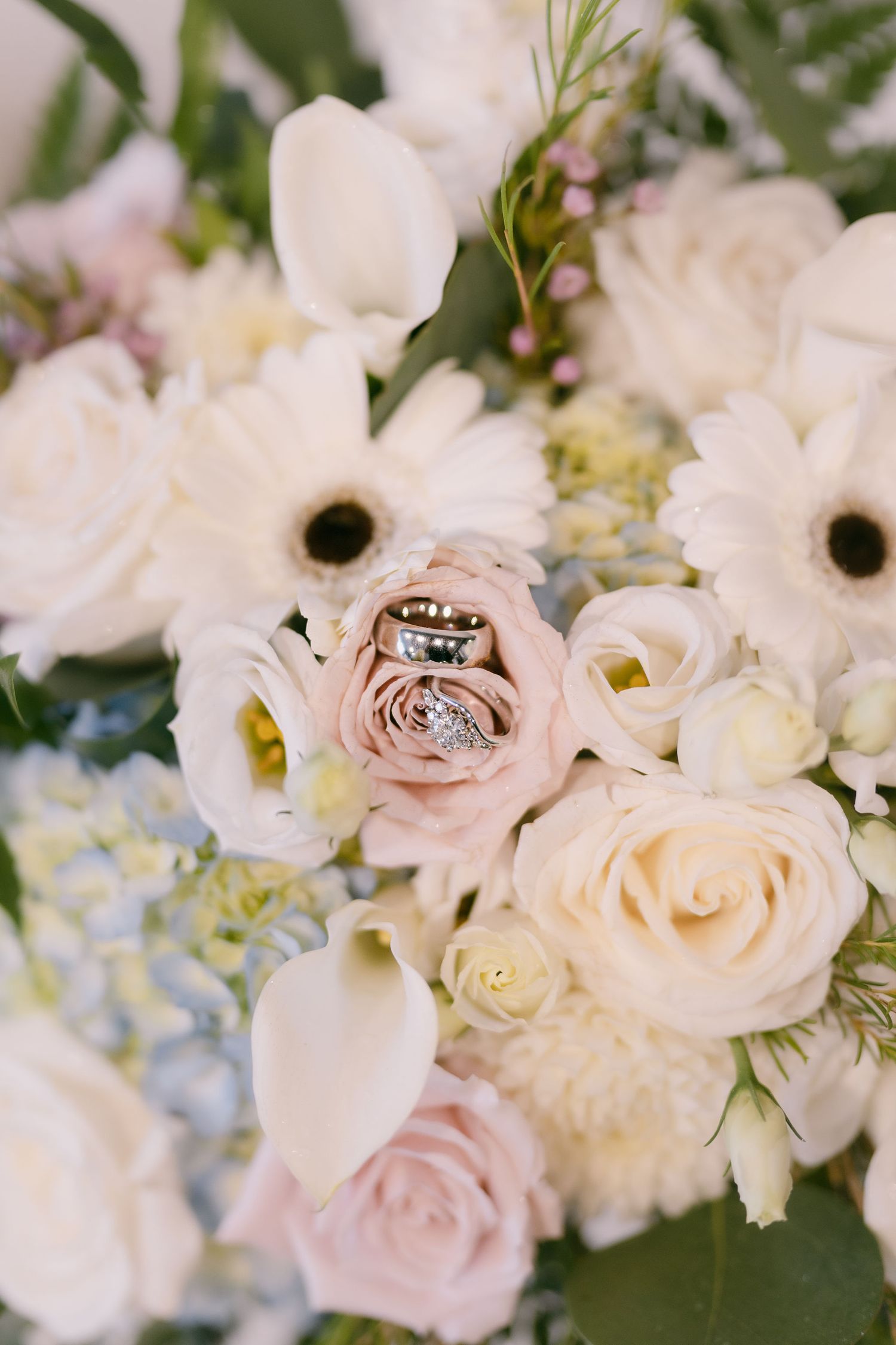 Close-up of delicate white and blush pink roses in a wedding floral arrangement.