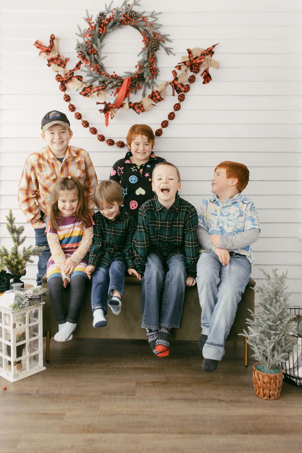 Family group sitting together on bench with festive fall decorations.