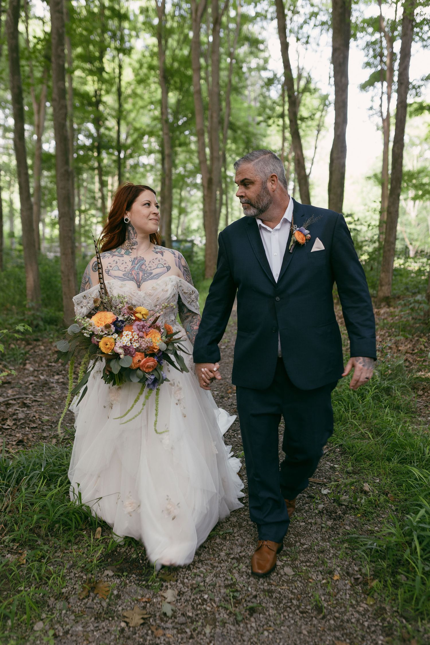 Romantic forest wedding portraits with couple walking among tall trees.