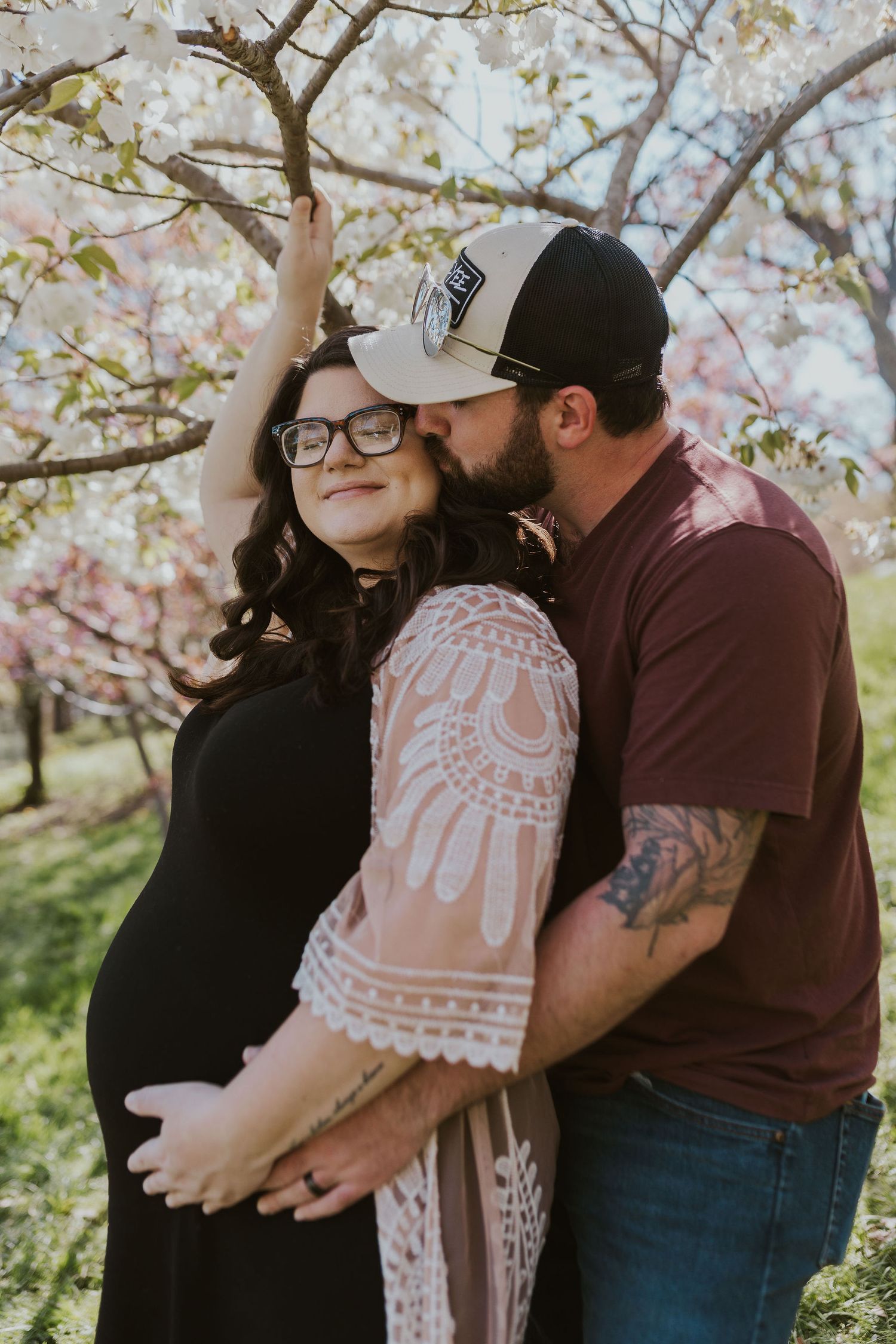 Romantic couple sharing tender moments under flowering spring trees.
