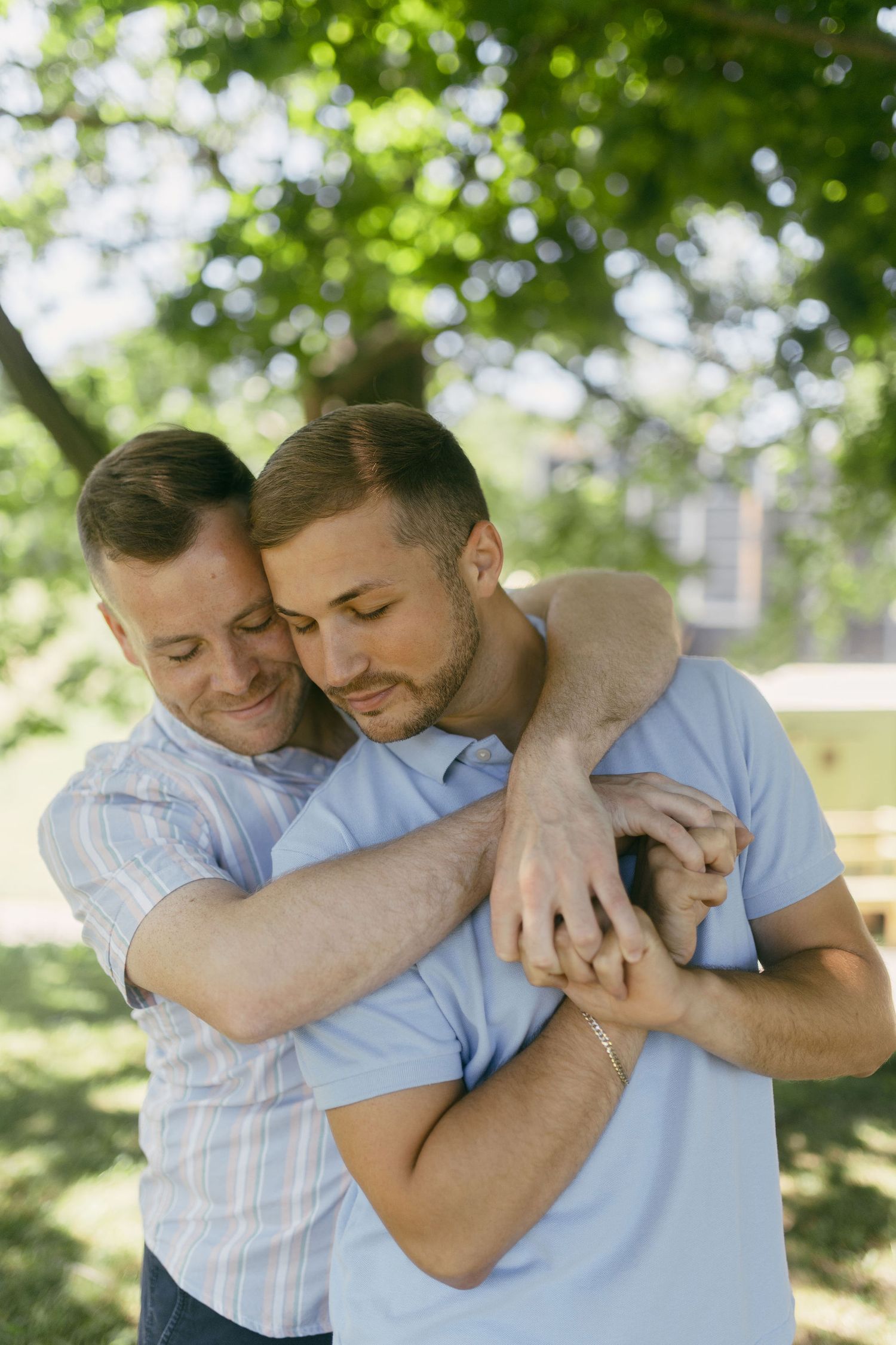 Tender embraces captured in natural sunlight under green summer foliage.