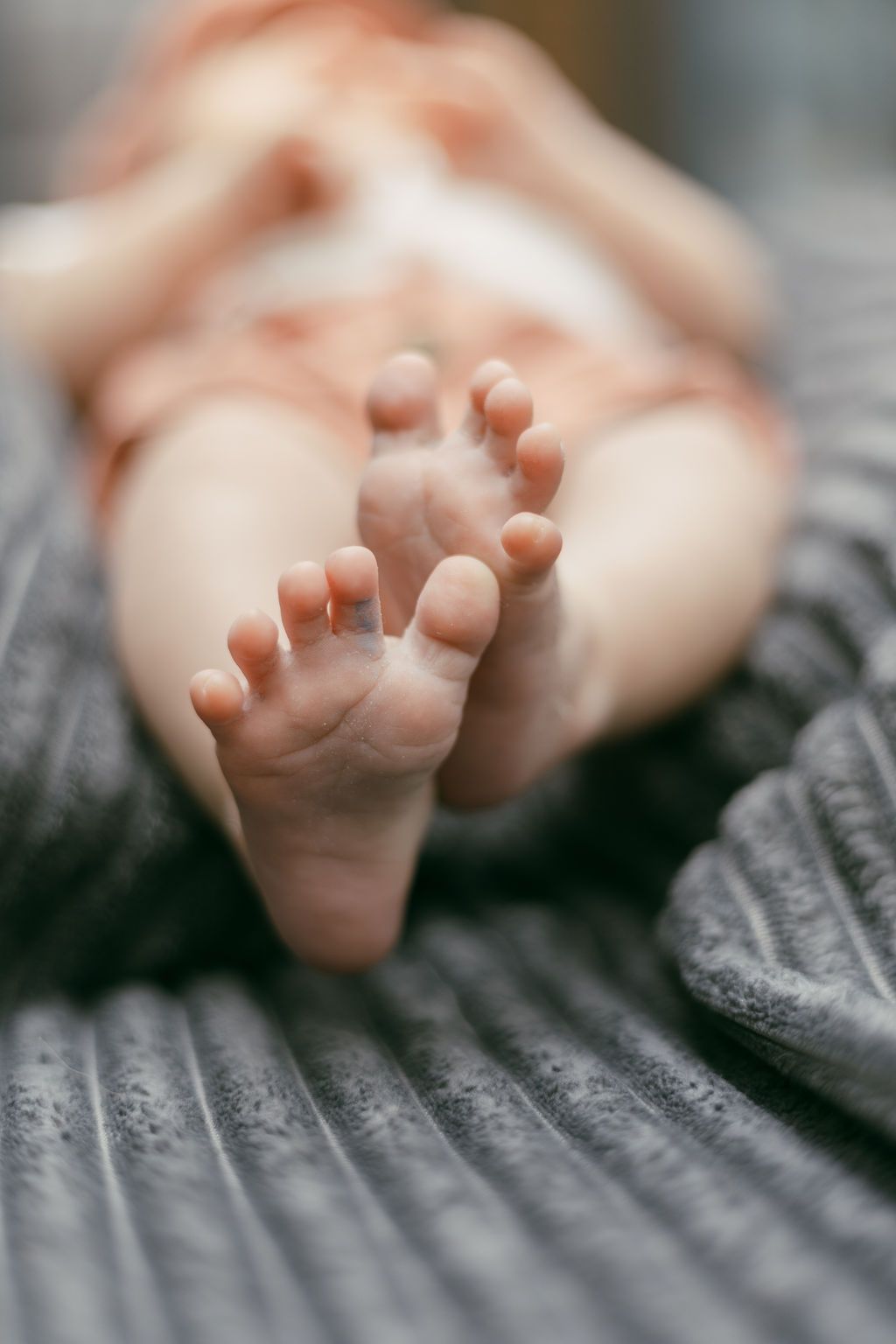 Close-up view of tiny baby toes against a gray textured background.