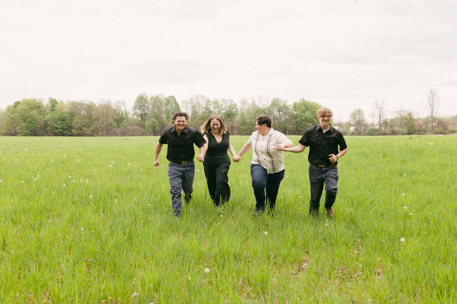 People walk together across a vast green meadow on a cloudy spring day.