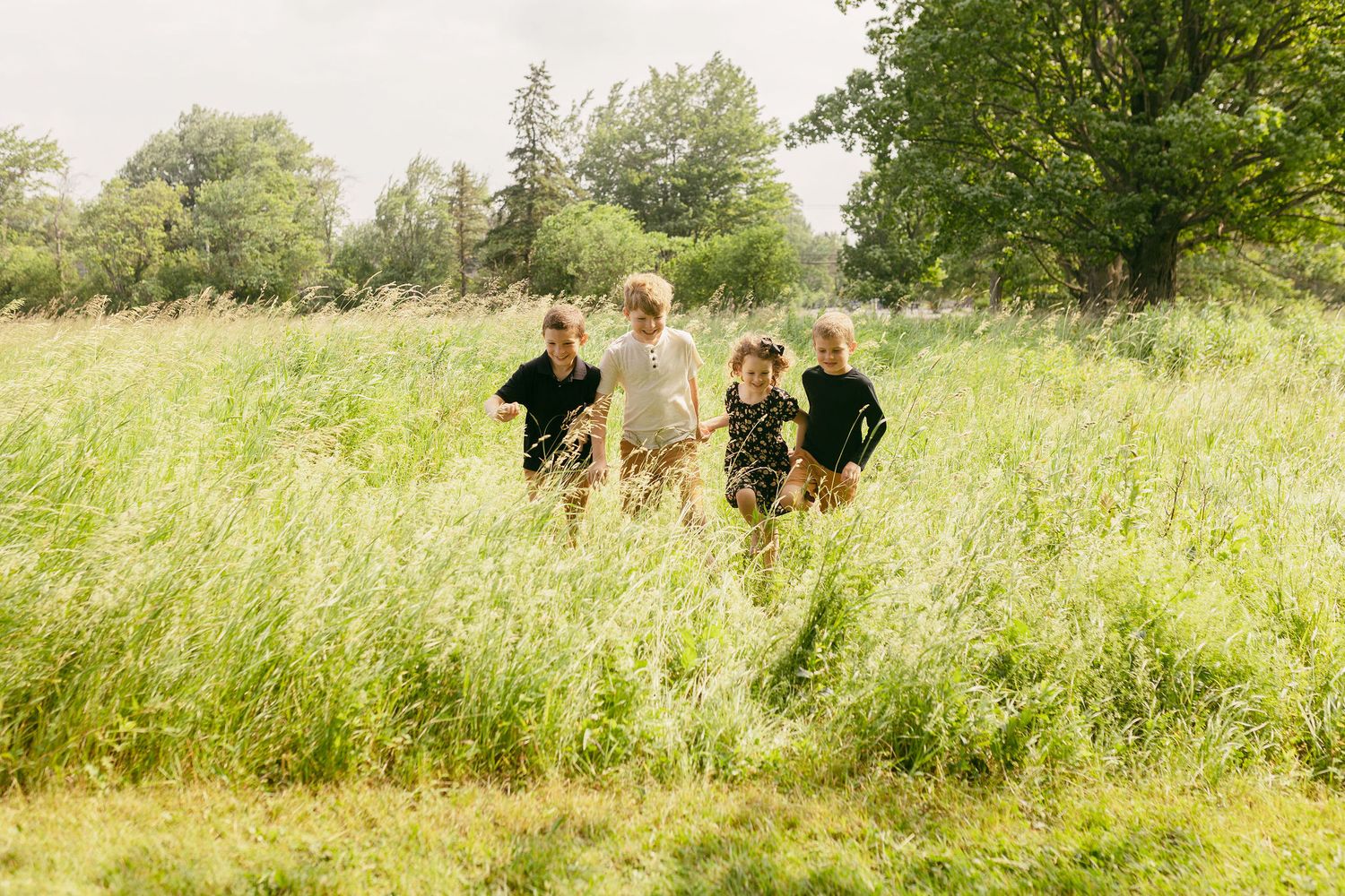 Outdoor portrait session in tall grass meadow with soft natural lighting.