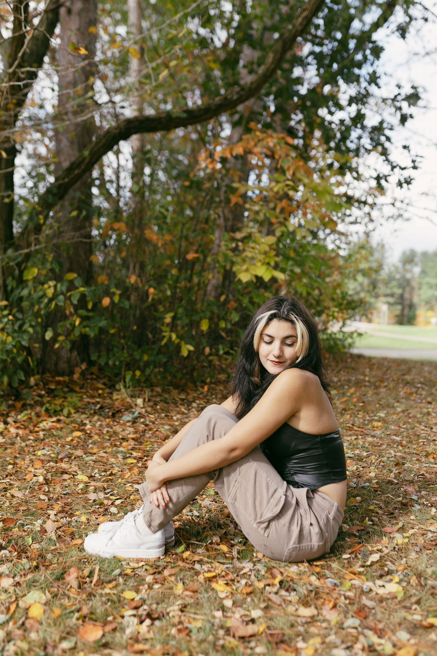 Casual outdoor portraits in beige and black attire among fallen autumn leaves.