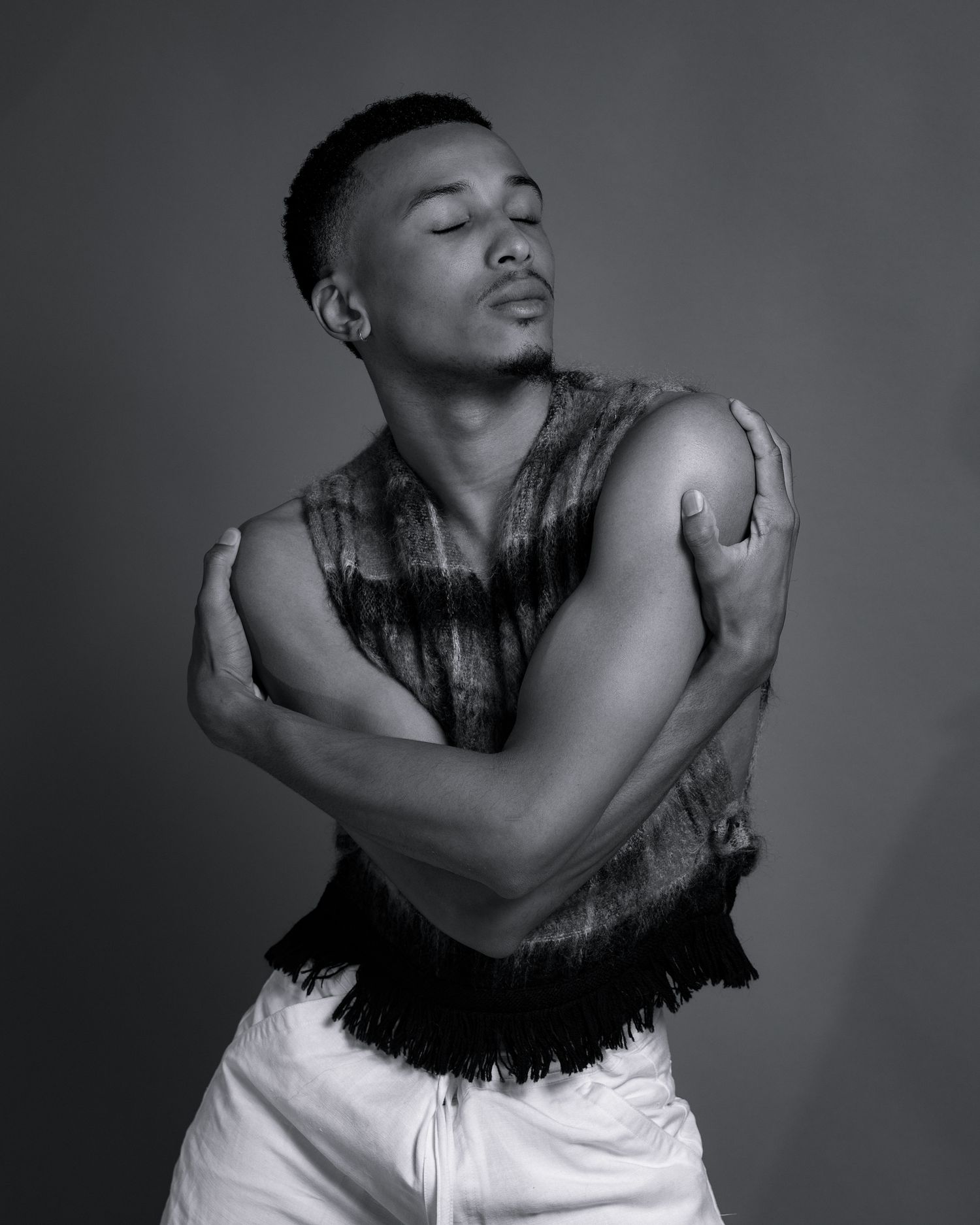 Artistic black and white portrait showing intimate embrace against dark background.