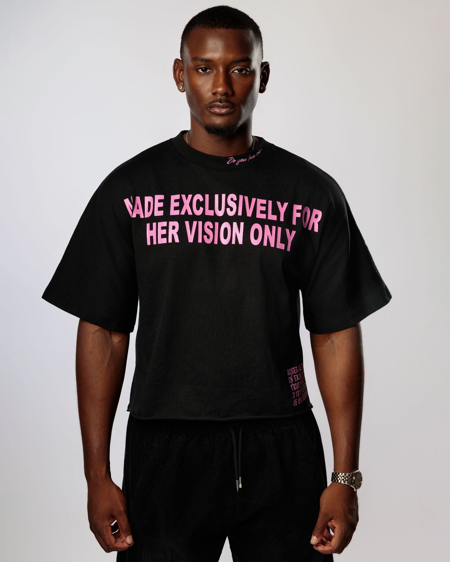 Black t-shirt with pink text reading 'HER VISION ONLY' shown in studio lighting against white background.