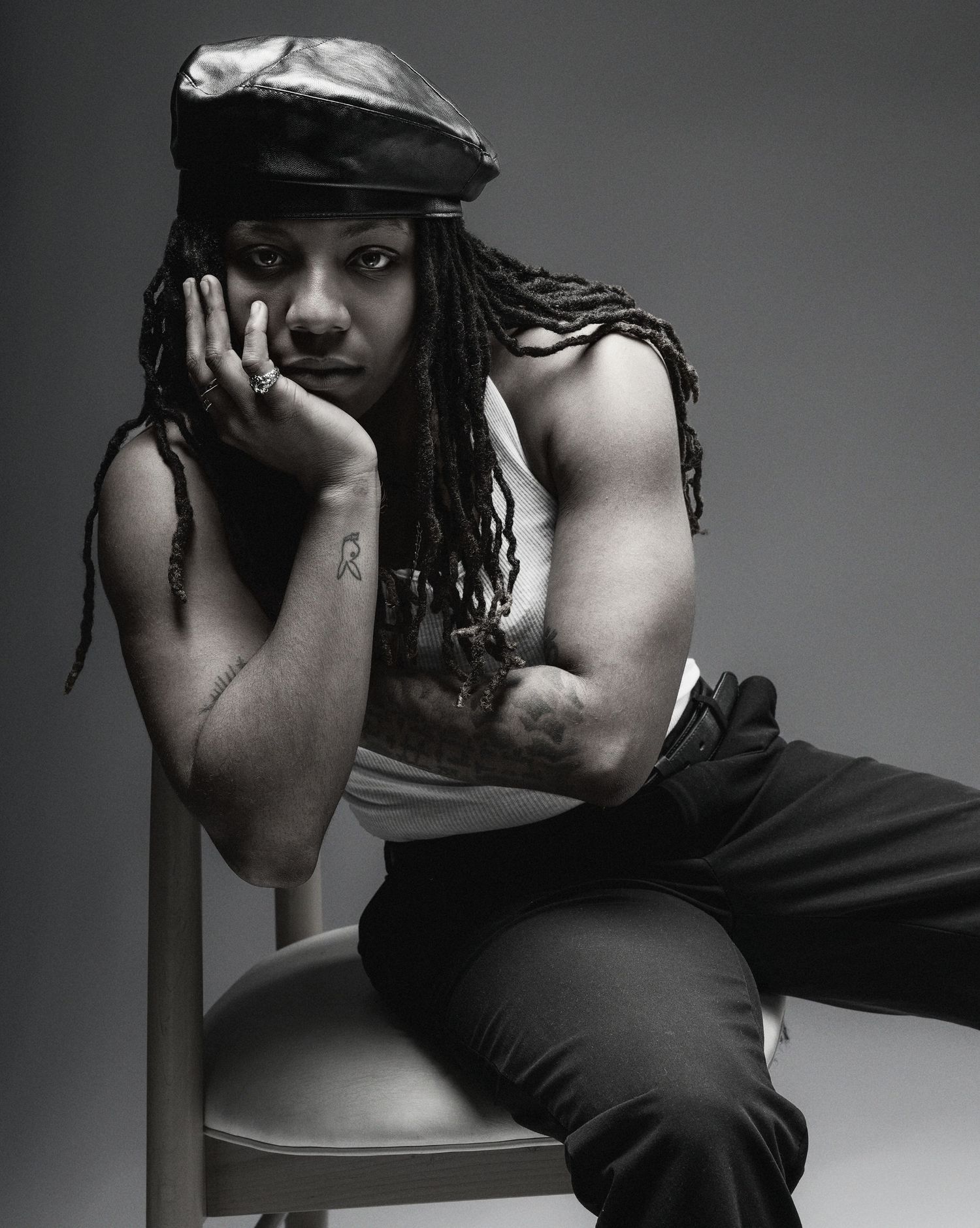 Dramatic black and white portrait series showing person with dreadlocks in artistic poses against dark background.