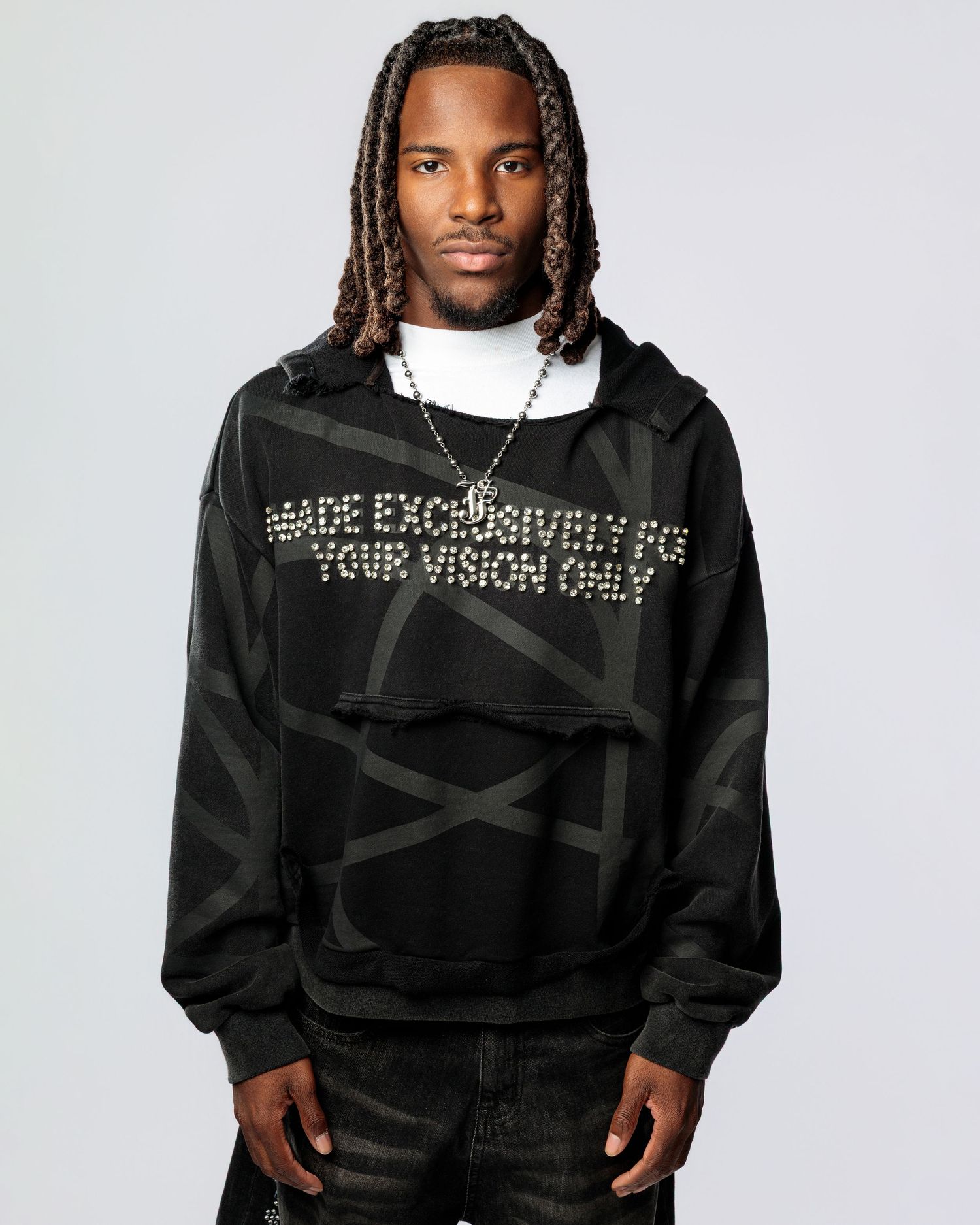 Athletic model wearing black streetwear hoodie with reflective text design in urban fashion photoshoot.