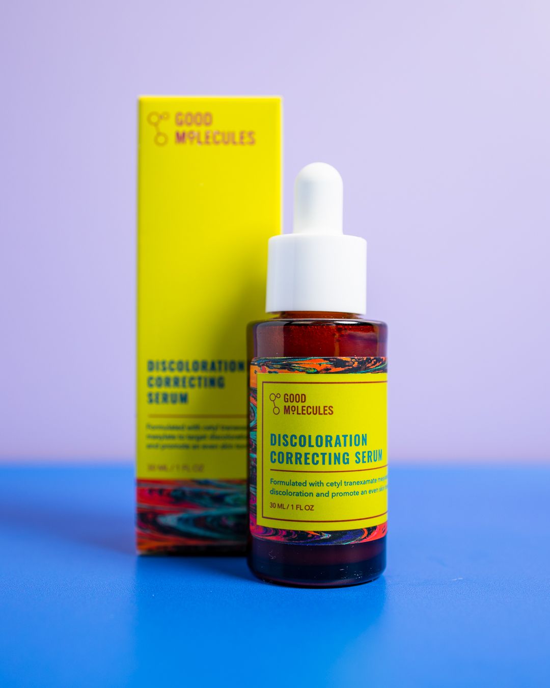 Amber glass bottle of skincare serum with bright yellow packaging against blue and purple gradient background.