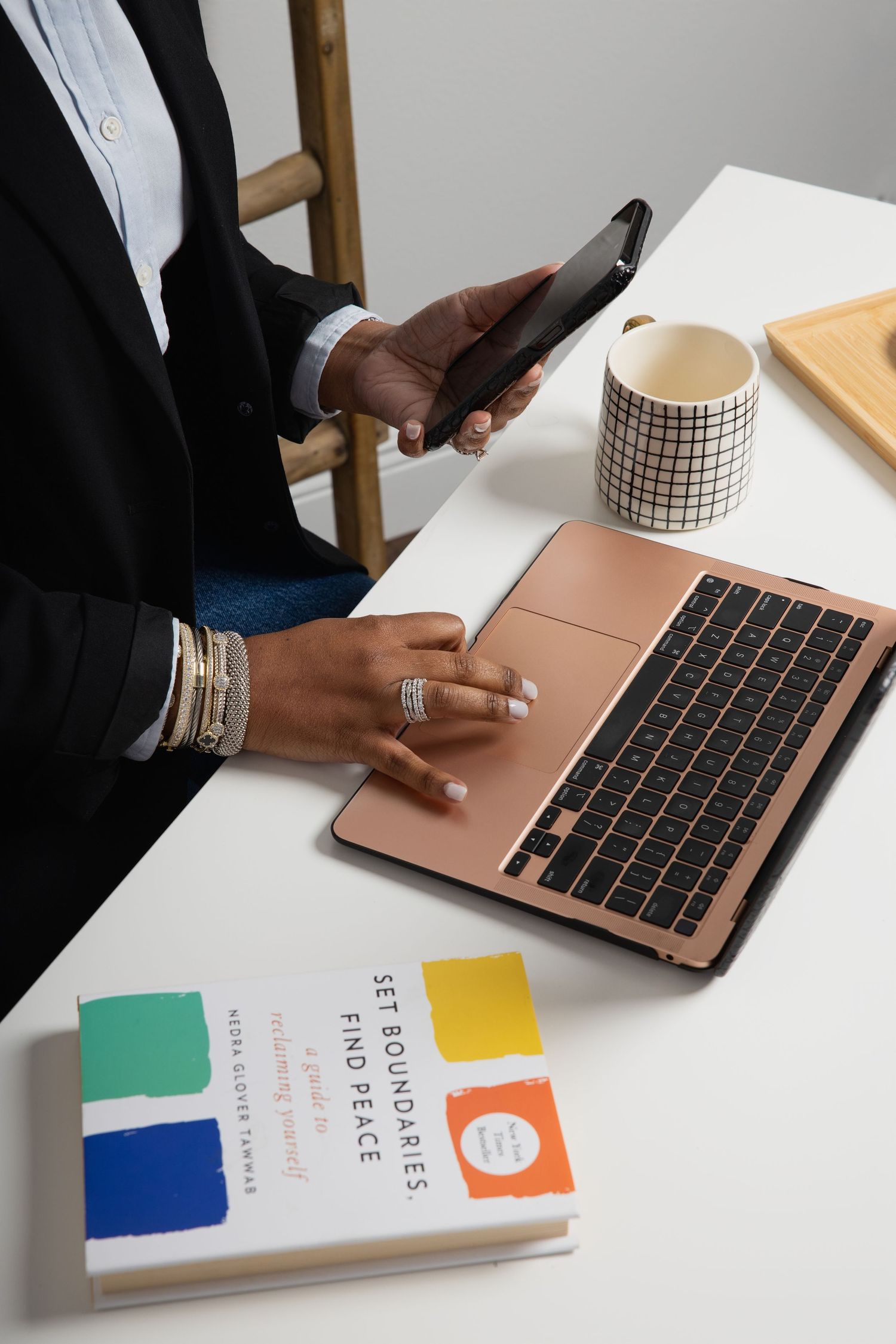 Closeup of hands working on rose gold laptop with colorful business materials.