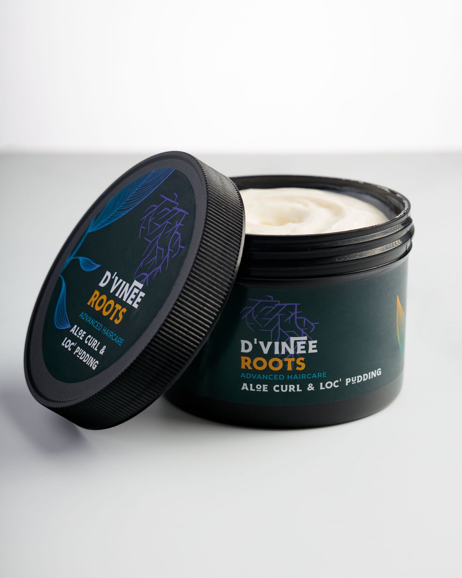An open jar of D'Vinee Roots hair styling product with black lid and blue label showing cream-colored contents inside.