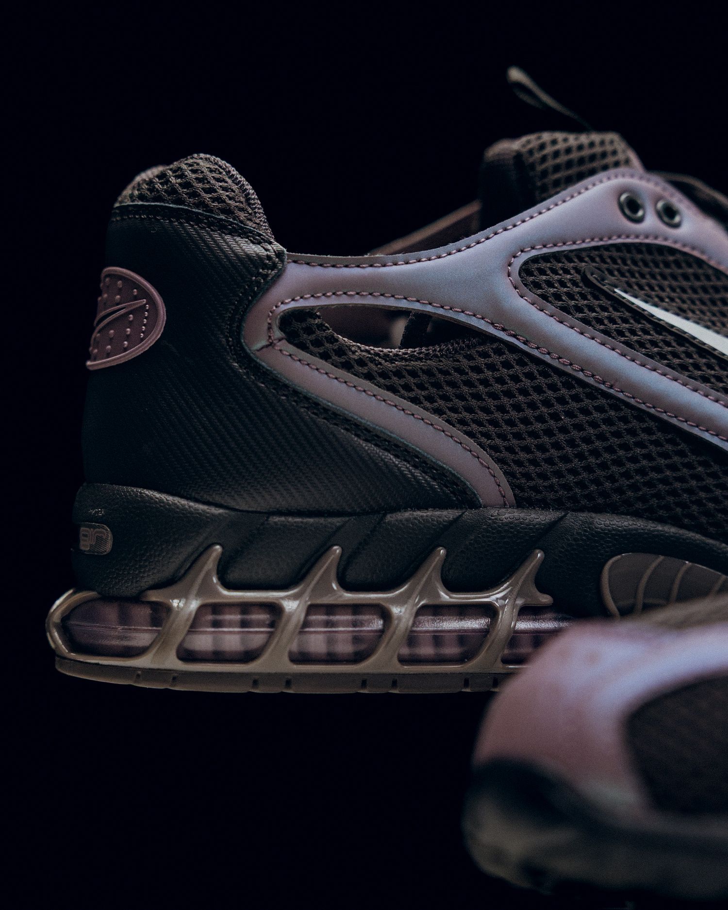 Close-up view of black and gray athletic shoe sole design showing cushioning details in dark lighting.