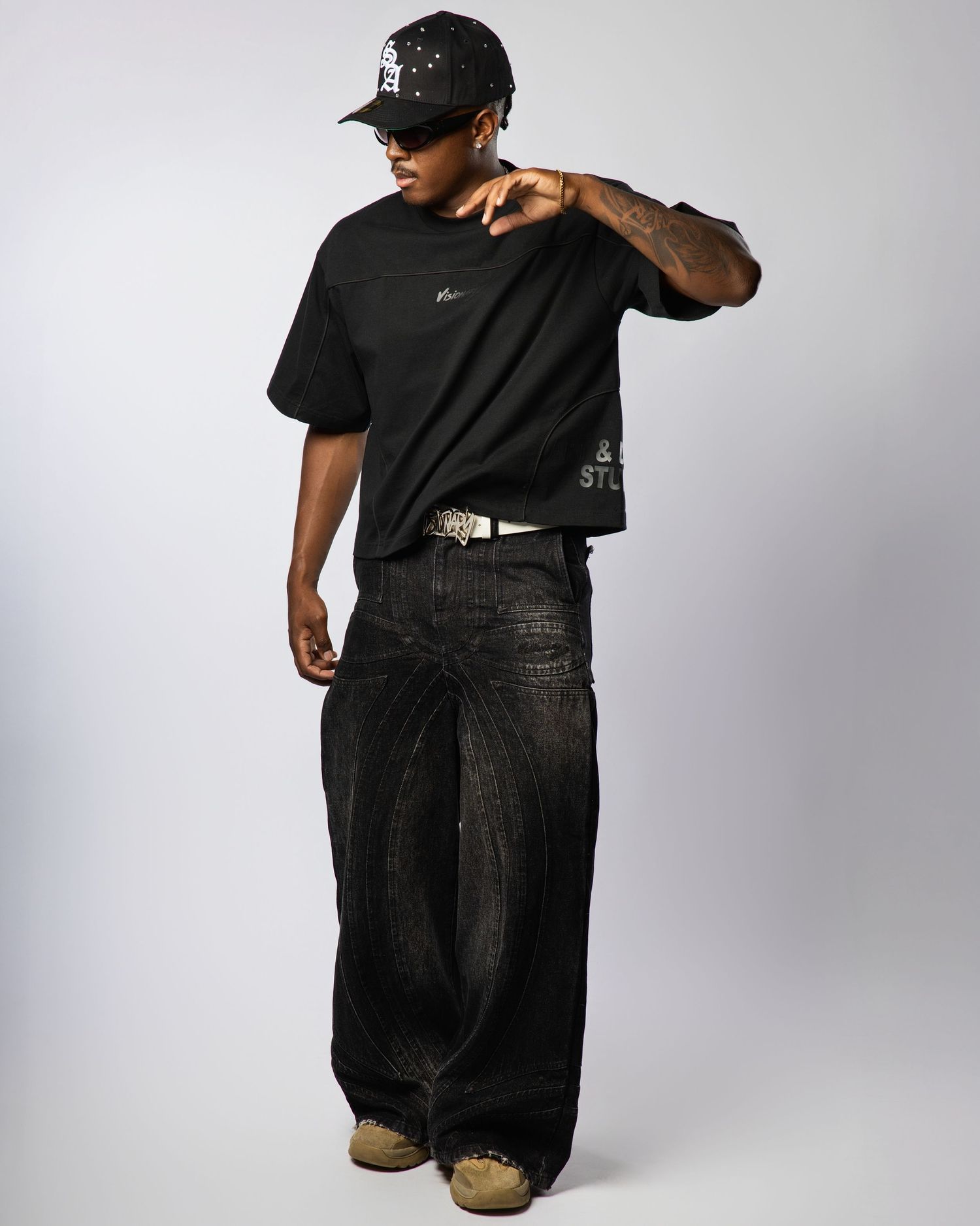 Person wearing black clothing and cap poses in multiple angles against a light background, showcasing casual urban style.