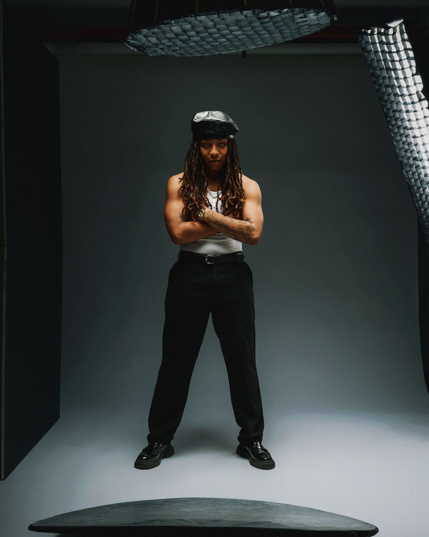 Dramatic sequence of a person in black clothing crouching and posing against a white studio backdrop with overhead lighting.