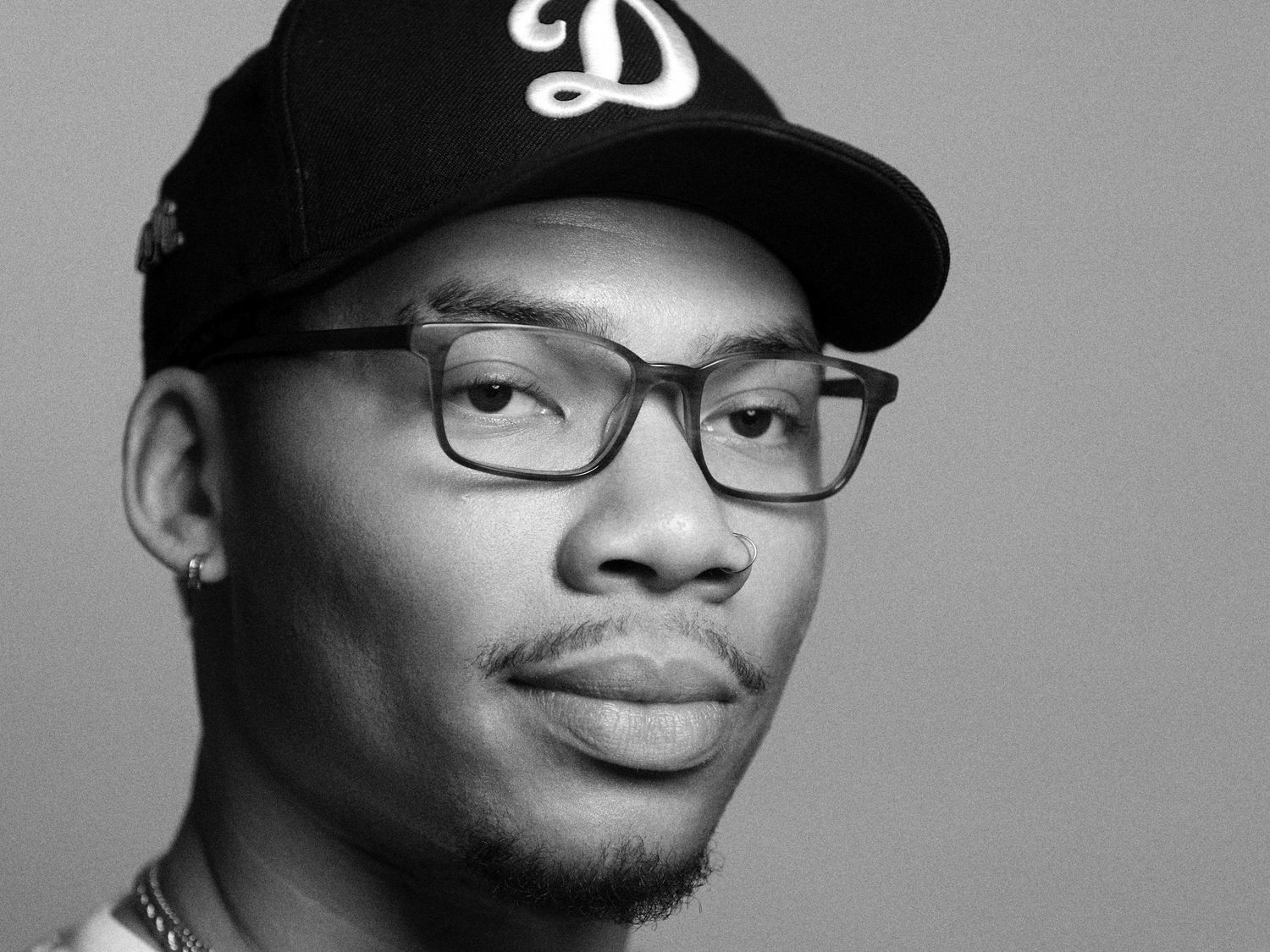 A series of black and white headshots showing different angles of a person wearing glasses and a baseball cap.