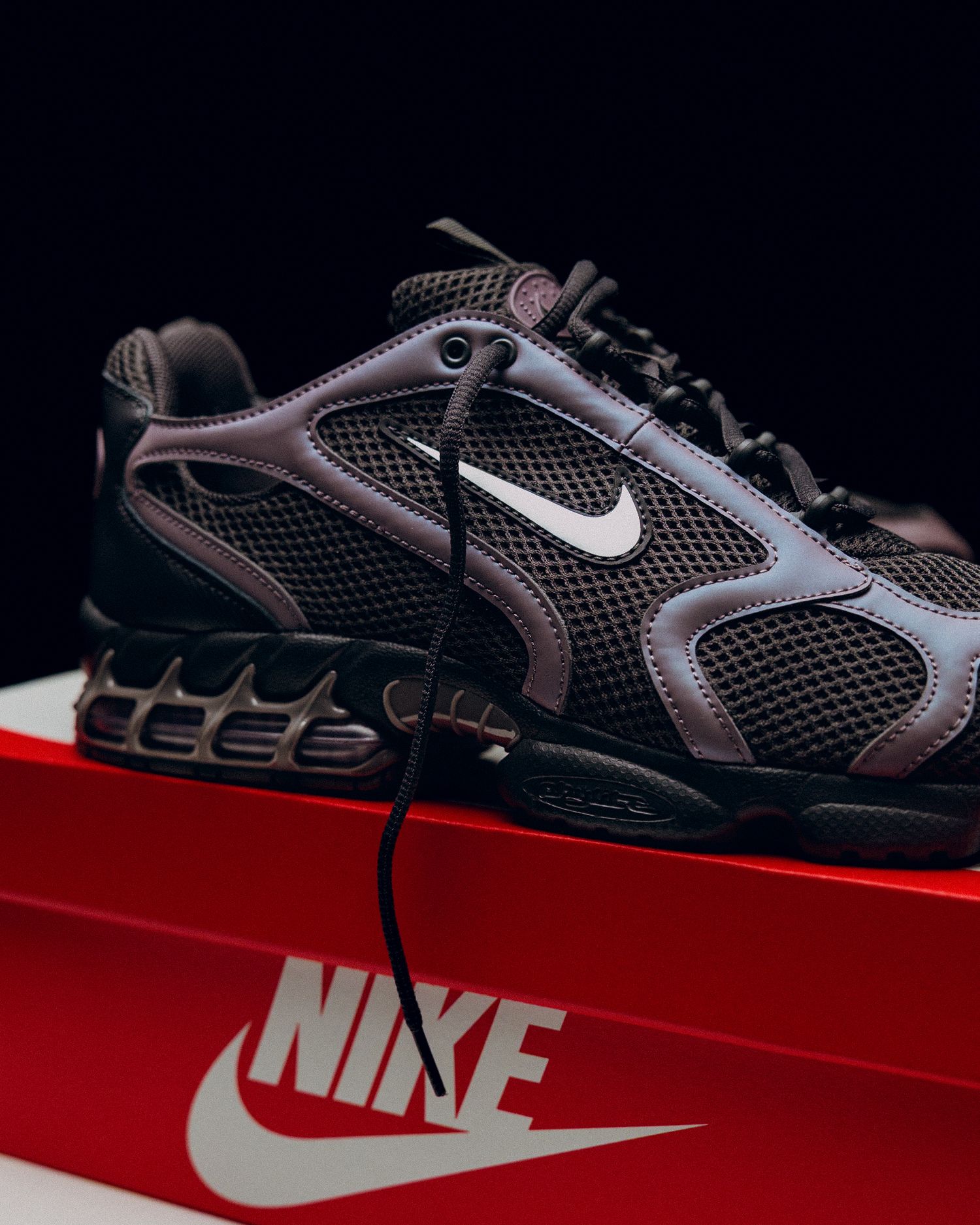Nike athletic shoe displayed on a red platform showcasing its black mesh design and white swoosh logo.