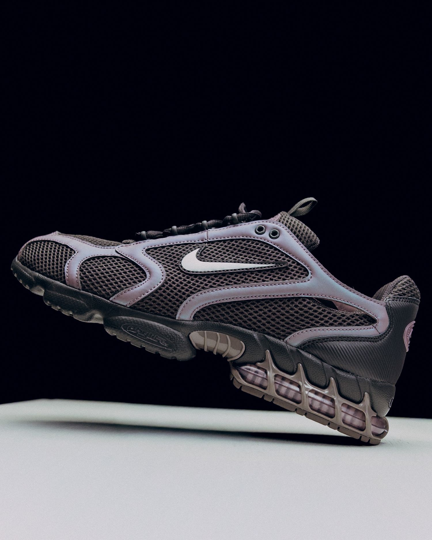 Nike running shoe in black and silver mesh design shown from multiple angles against dark background.