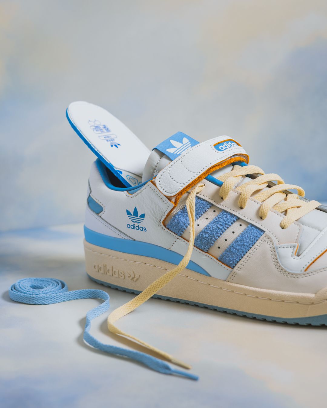 Vintage white and blue leather tennis shoes shown from multiple angles against a soft blue background.